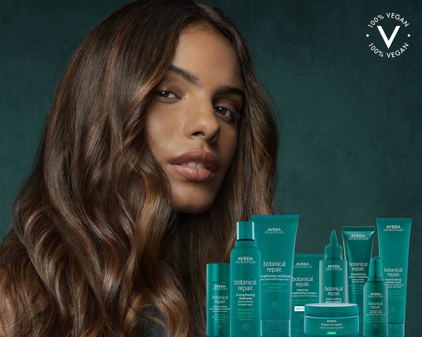 Een vrouw met golvend bruin haar staat voor een collectie AVEDA Botanical Repair haarproducten in groene verpakkingen, allemaal 100% vegan.