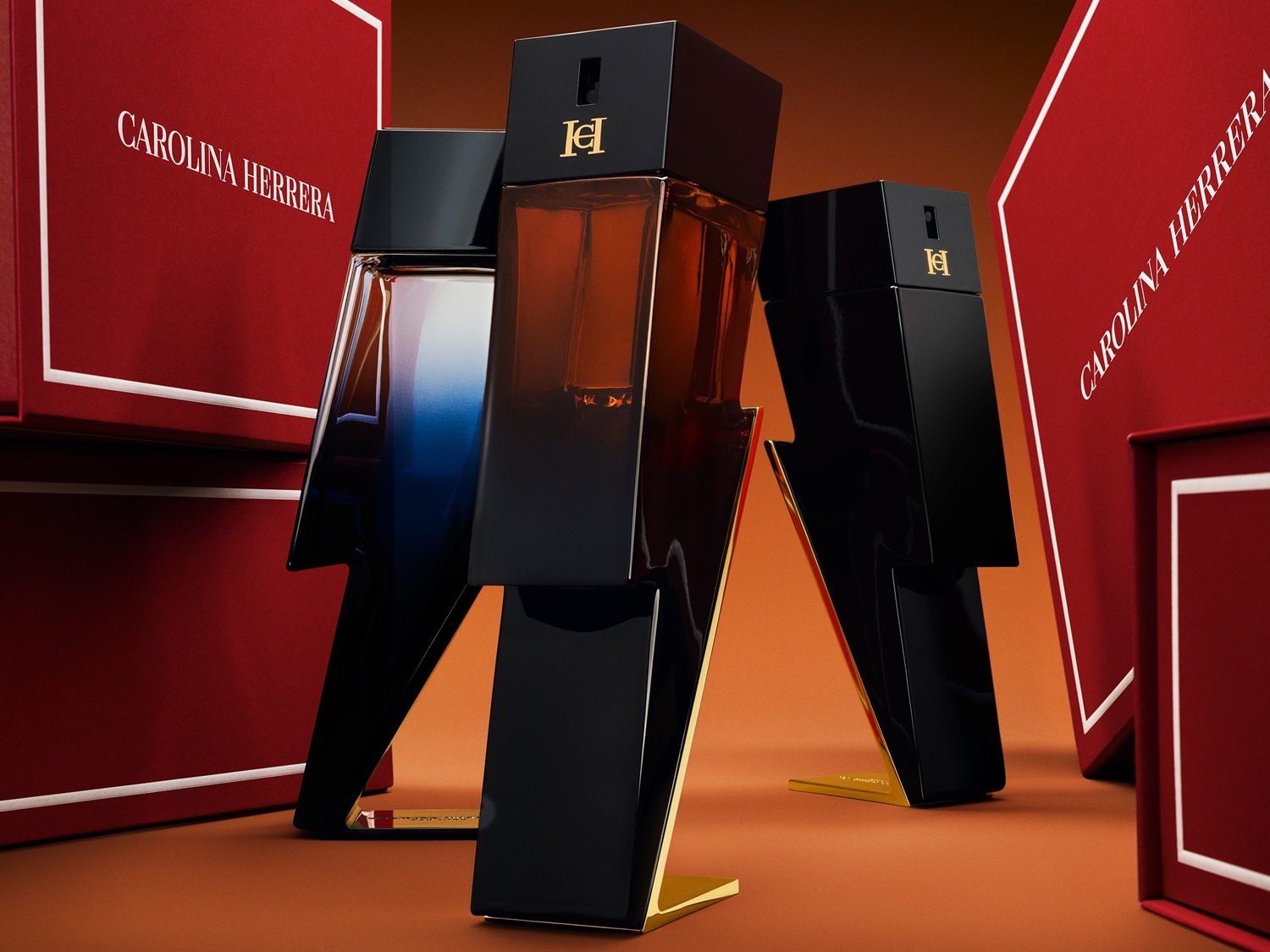 Tri flakóny pánskeho parfumu Carolina Herrera Bad Boy v tvare čierneho blesku so zlatými detailmi stoja vedľa červených darčekových krabičiek s nápisom Carolina Herrera.