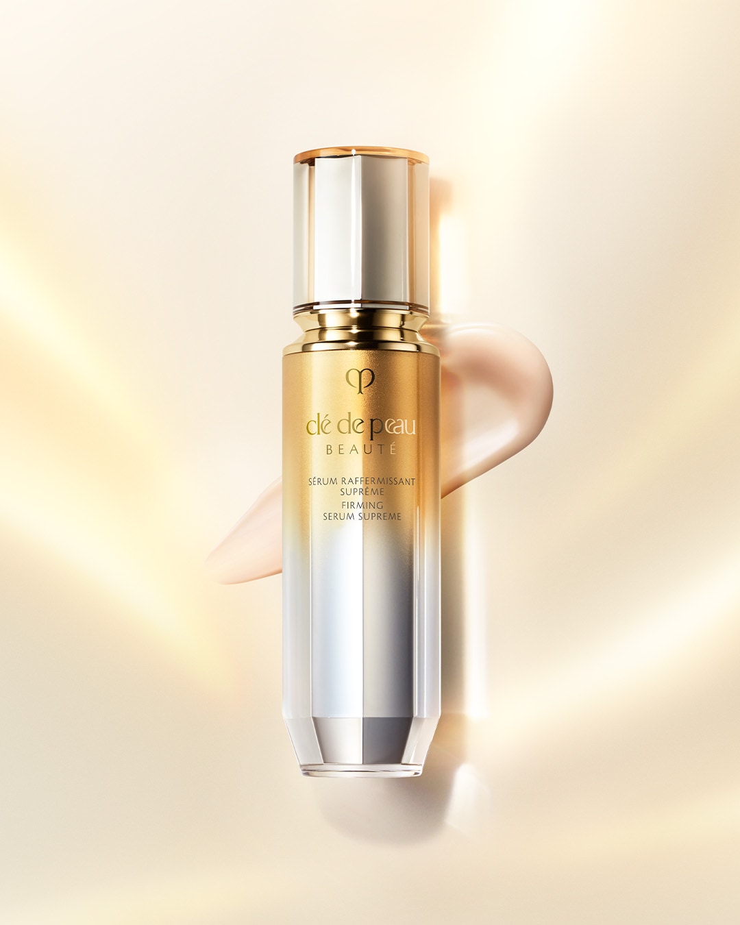 Das Clé de Peau Beauté Serum Supreme in einer eleganten, goldenen und silbernen Flasche, umgeben von einem Hauch von Serum, verspricht straffende Wirkung.