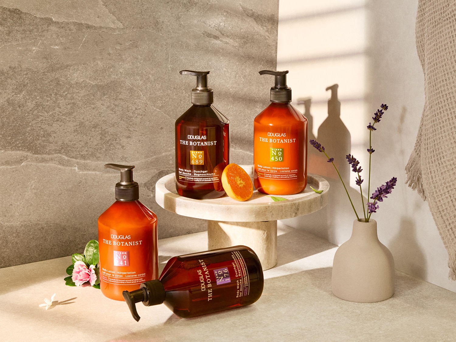 Découvrez la collection Douglas The Botanist, comprenant des lotions et gels douche dans des flacons orange et marron, présentés avec des fleurs et des agrumes.