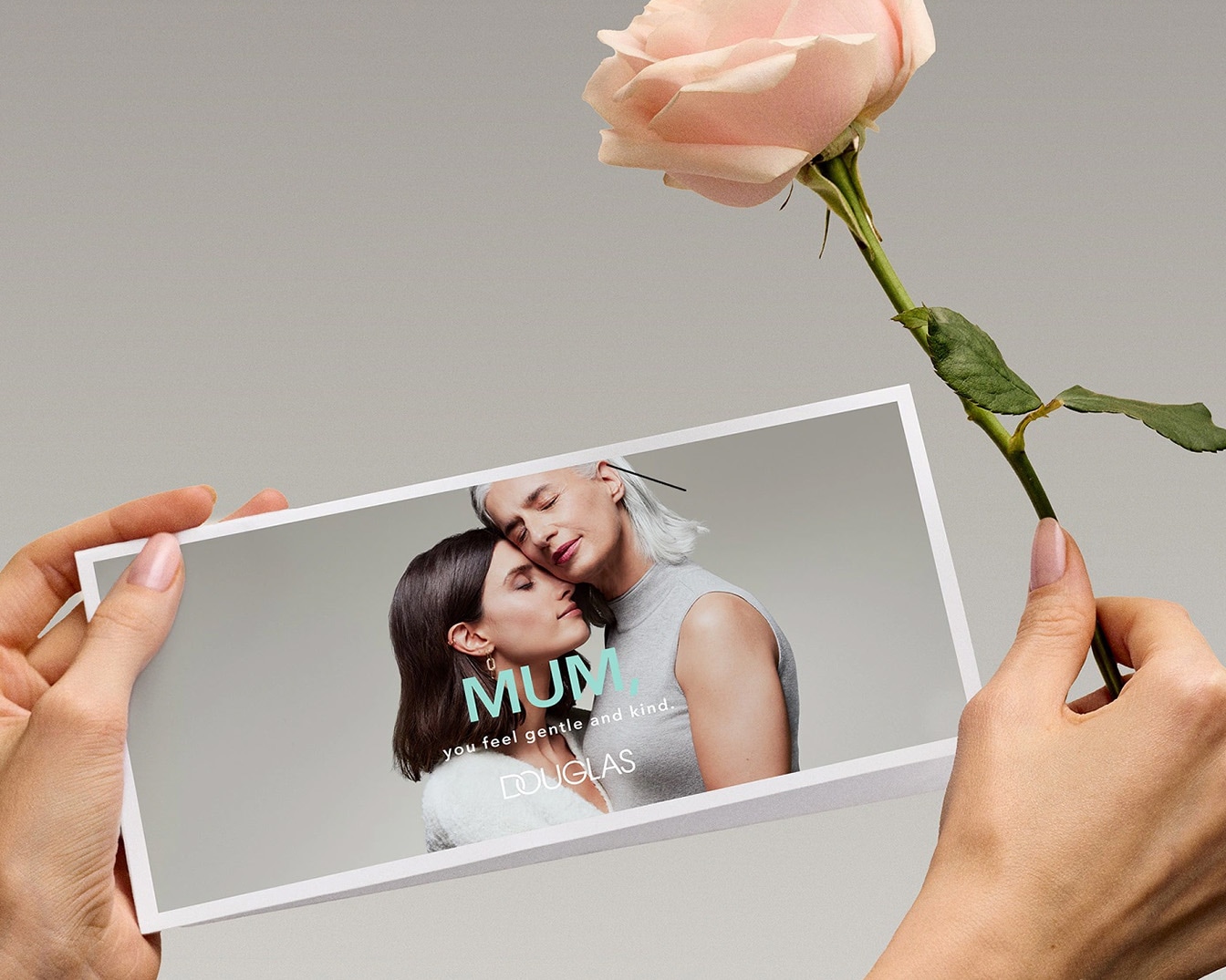 Una mano tiene una foto di una madre e una figlia che si abbracciano, con un testo che dice 'Mamma, ti senti gentile e premurosa' e un rosa color pesca.