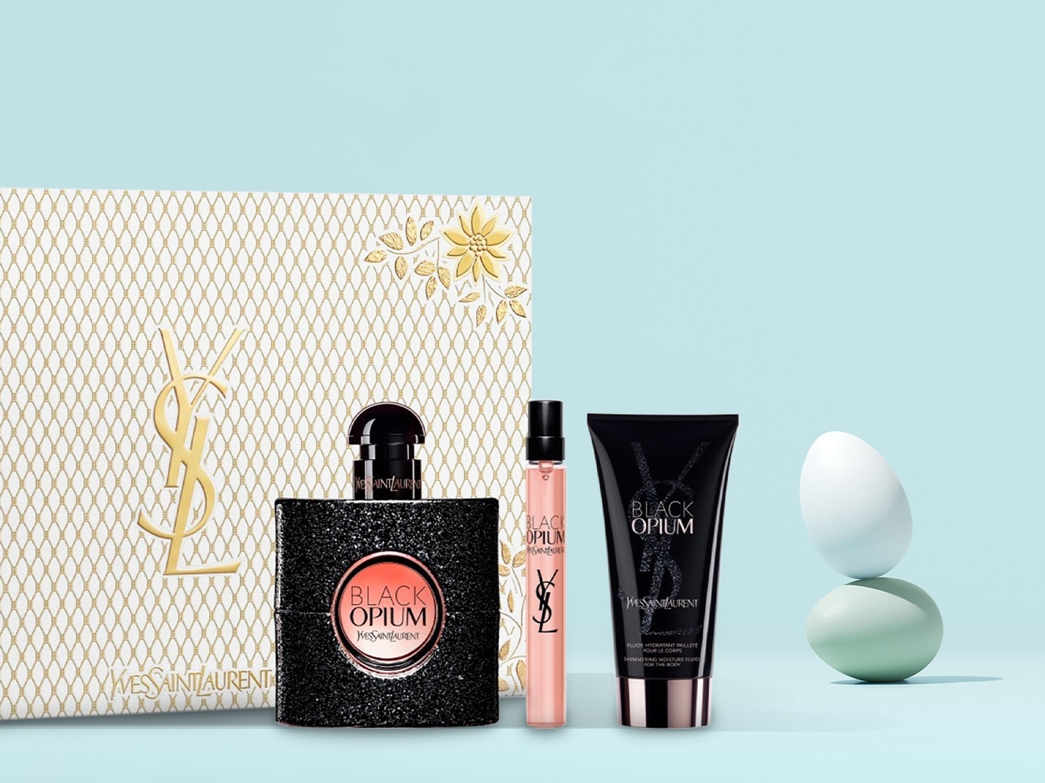 Découvrez le coffret Black Opium d'Yves Saint Laurent, comprenant un parfum scintillant, un vaporisateur de voyage et une lotion hydratante pour le corps, le tout présenté dans un élégant emballage doré.
