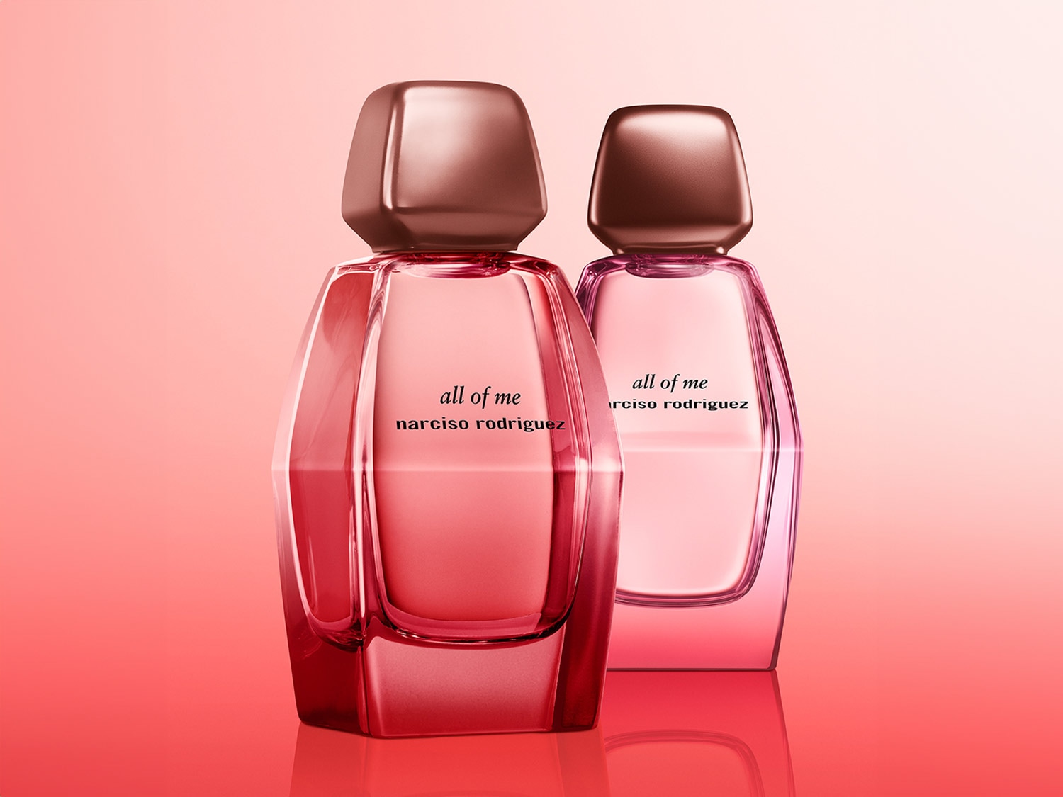 Dos frascos de perfume 'all of me' de Narciso Rodriguez, uno en tonos rojizos y otro en rosados, ambos con tapones metálicos brillantes.