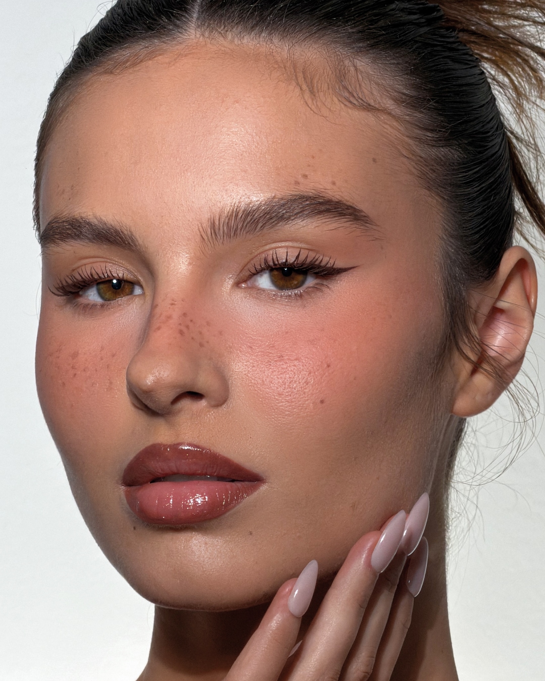 Primer plano de un rostro con maquillaje natural, resaltando labios brillantes, piel luminosa y sutiles toques de rubor.