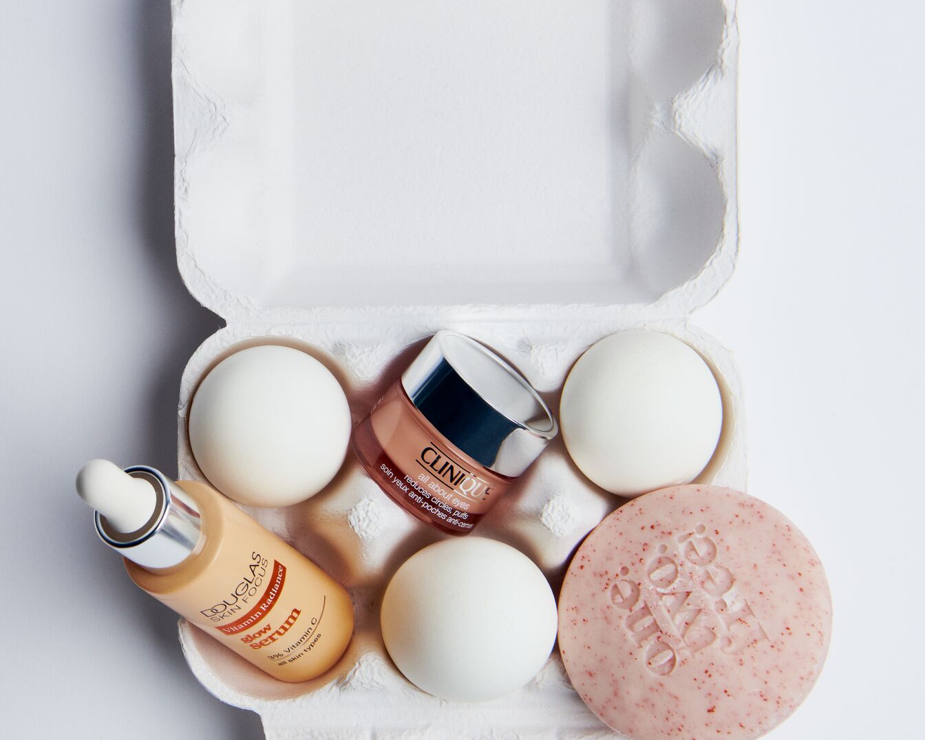 Een eierdoos bevat een Douglas Skin Focus vitamine C serum, een Clinique oogcrème, een roze zeep en witte eieren.