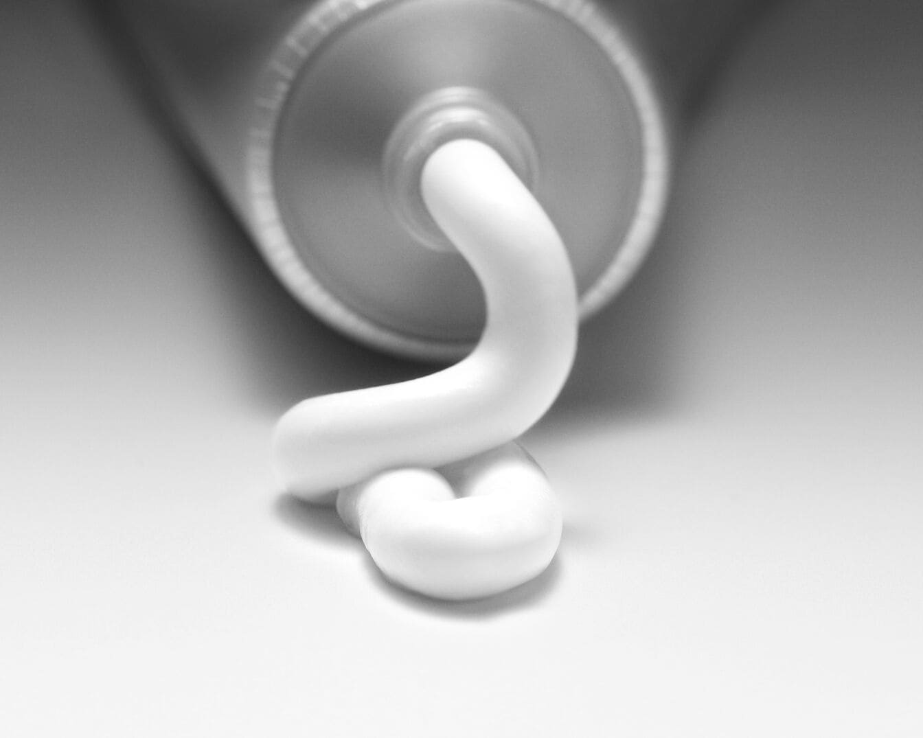 Sidabrinis tūbelė su baltu kremu, išspaustu ant paviršiaus, paruoštas naudojimui.