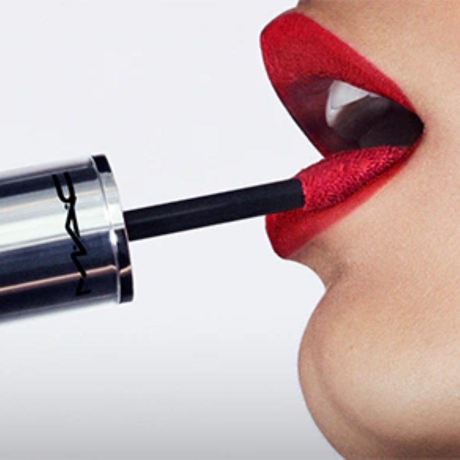Nahaufnahme einer Frau, die roten MAC Liquid Lipstick mit einem Applikator aufträgt.