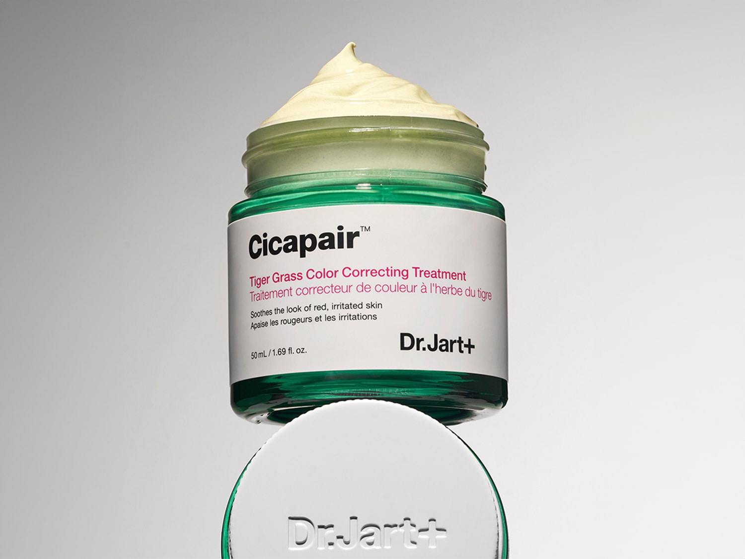 Voici le traitement correcteur de couleur à l'herbe du tigre Cicapair de Dr.Jart+ dans un pot en verre vert, conçu pour apaiser l'apparence des peaux rouges et irritées.