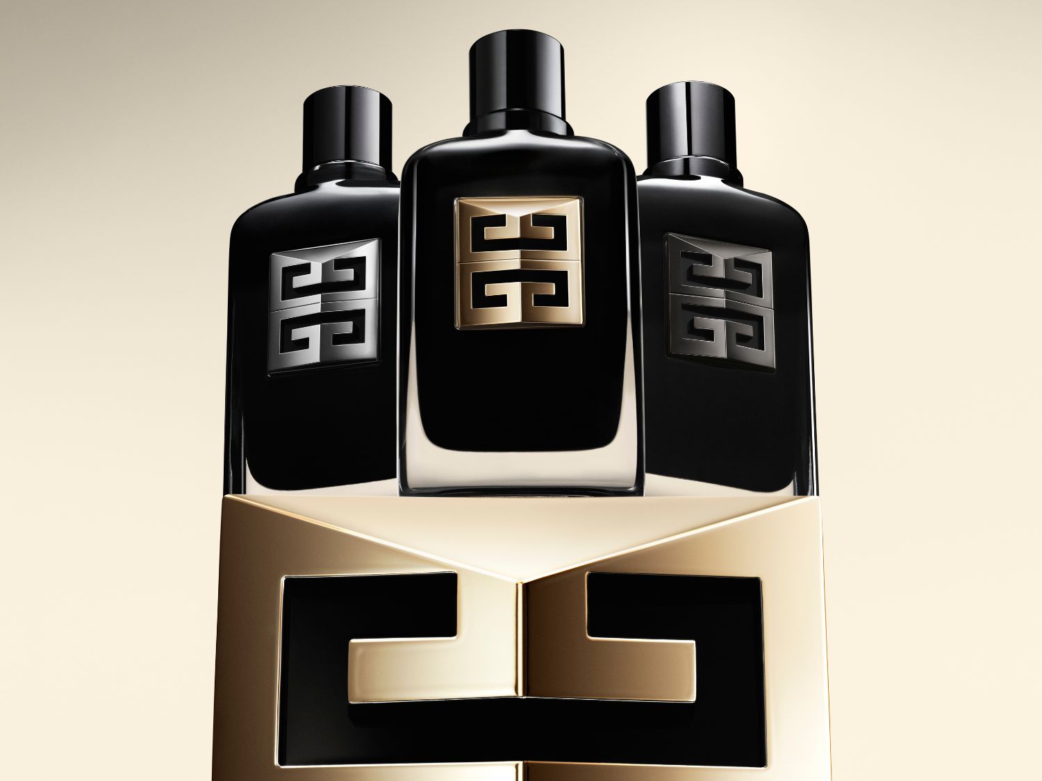 Trois flacons noirs Givenchy élégants, ornés du logo emblématique en or, argent et or, reposant sur un socle doré.