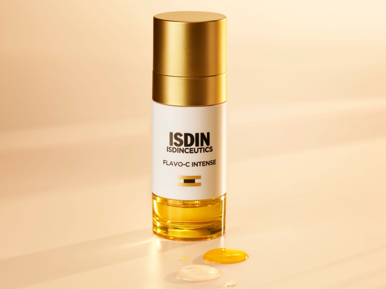 Aquí se muestra ISDIN Isdinceutics Flavo-C Intense en un envase blanco y dorado, con unas gotas del suero amarillo brillante que prometen una piel radiante.