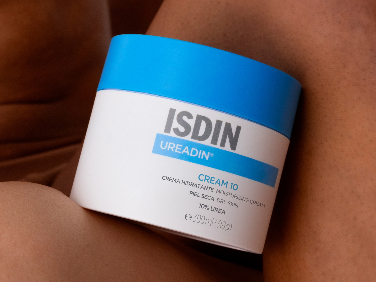 Aquí está ISDIN Ureadin Cream 10, una crema hidratante para piel seca con un 10% de urea, presentada en un envase blanco con detalles en azul.