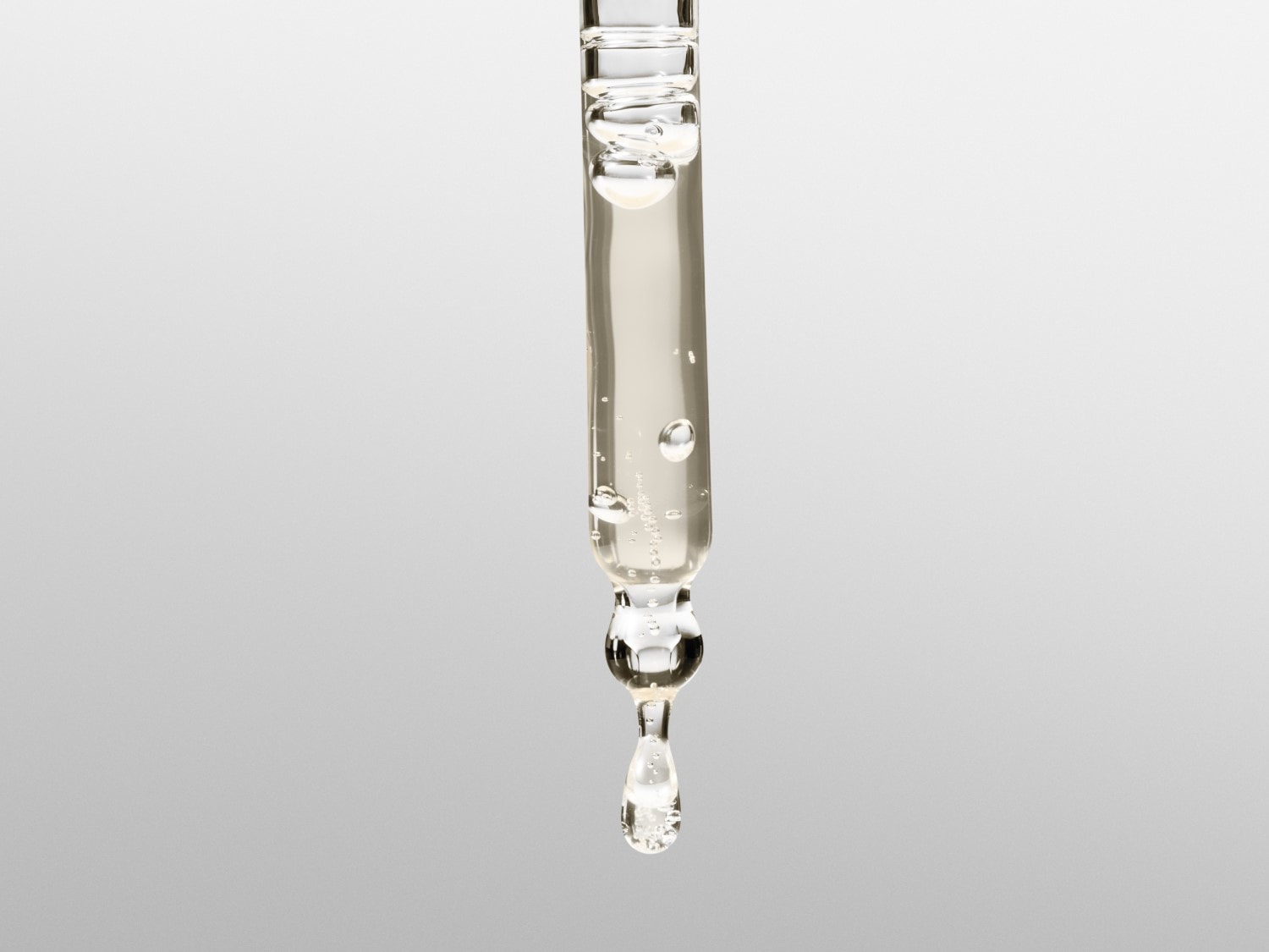 Skaidrus serumas su burbuliukais stikliniame pipetės aplikatoriuje, lašantis nuo galiuko.