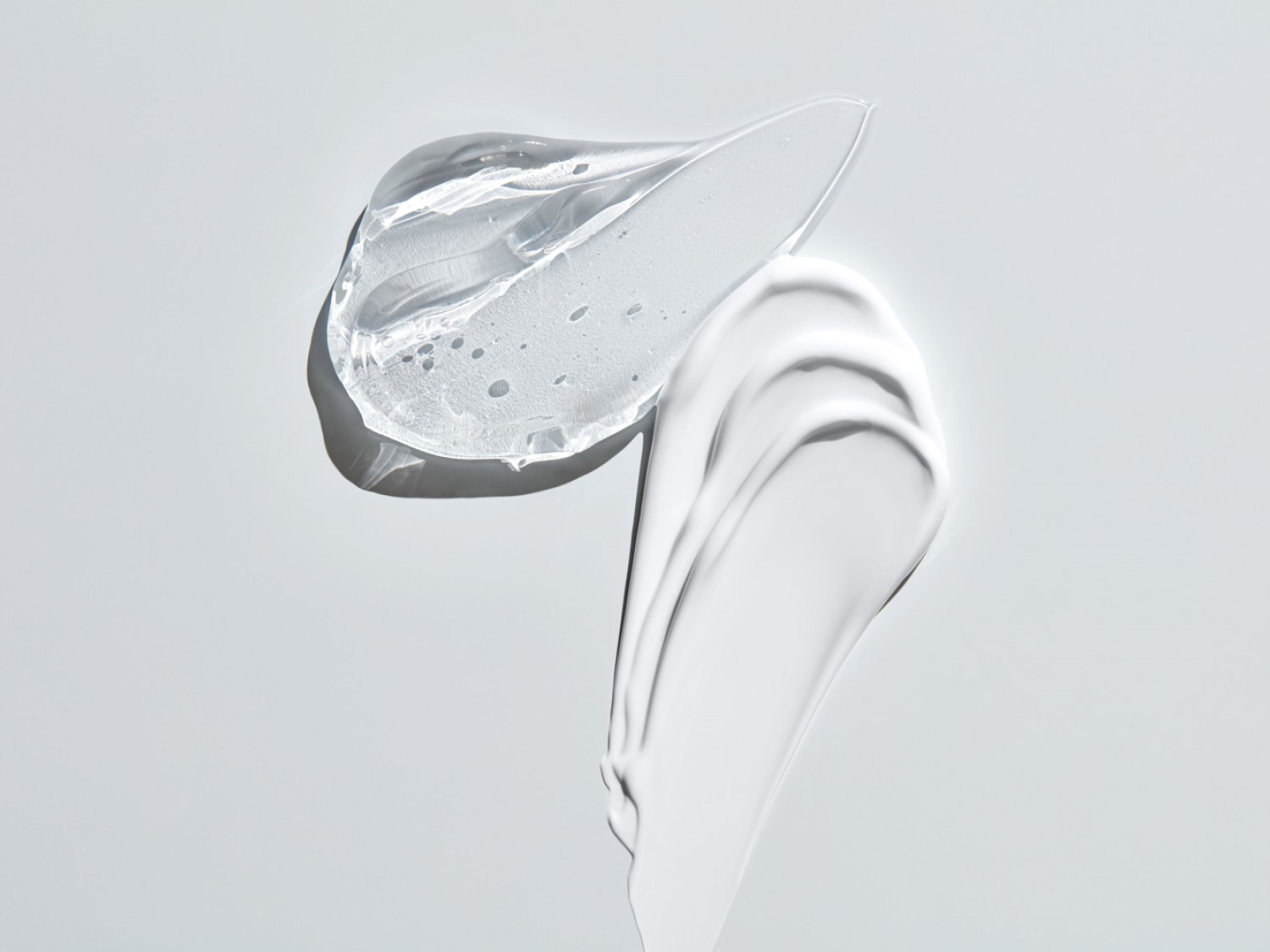 Een heldere gel en een witte crème liggen naast elkaar, klaar om je huid te verwennen met hydratatie en verzorging.