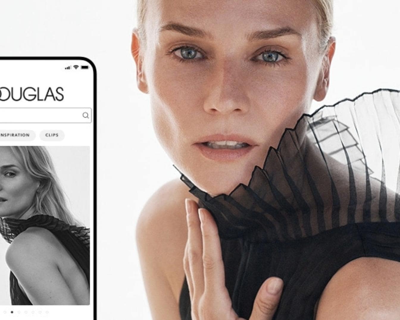 Primer plano de una mujer rubia con ojos azules y un vestido negro con volantes, junto a la pantalla de un móvil que muestra la página de inicio de Douglas.