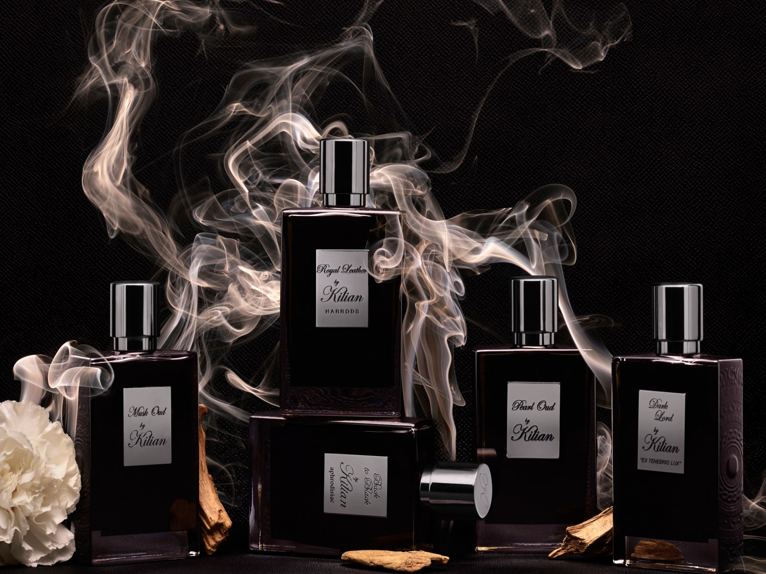 Elegancka kolekcja zapachów Kilian w ciemnych flakonach, otoczona subtelnym dymem, tworzy luksusową i tajemniczą aurę.