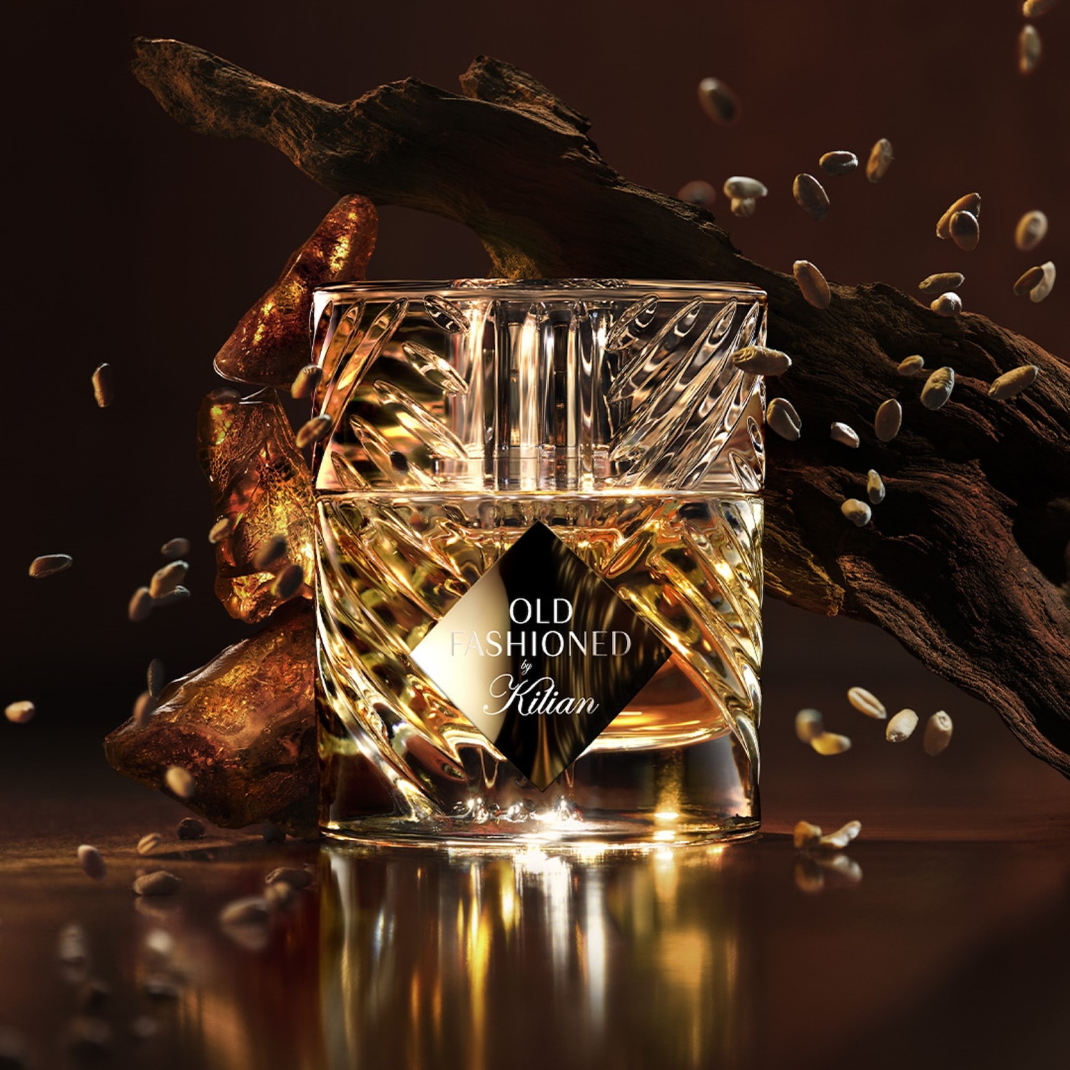 Kryształowy flakon perfum Kilian Old Fashioned, otoczony kawałkami drewna i ziaren, emanuje luksusem i wyrafinowaniem.