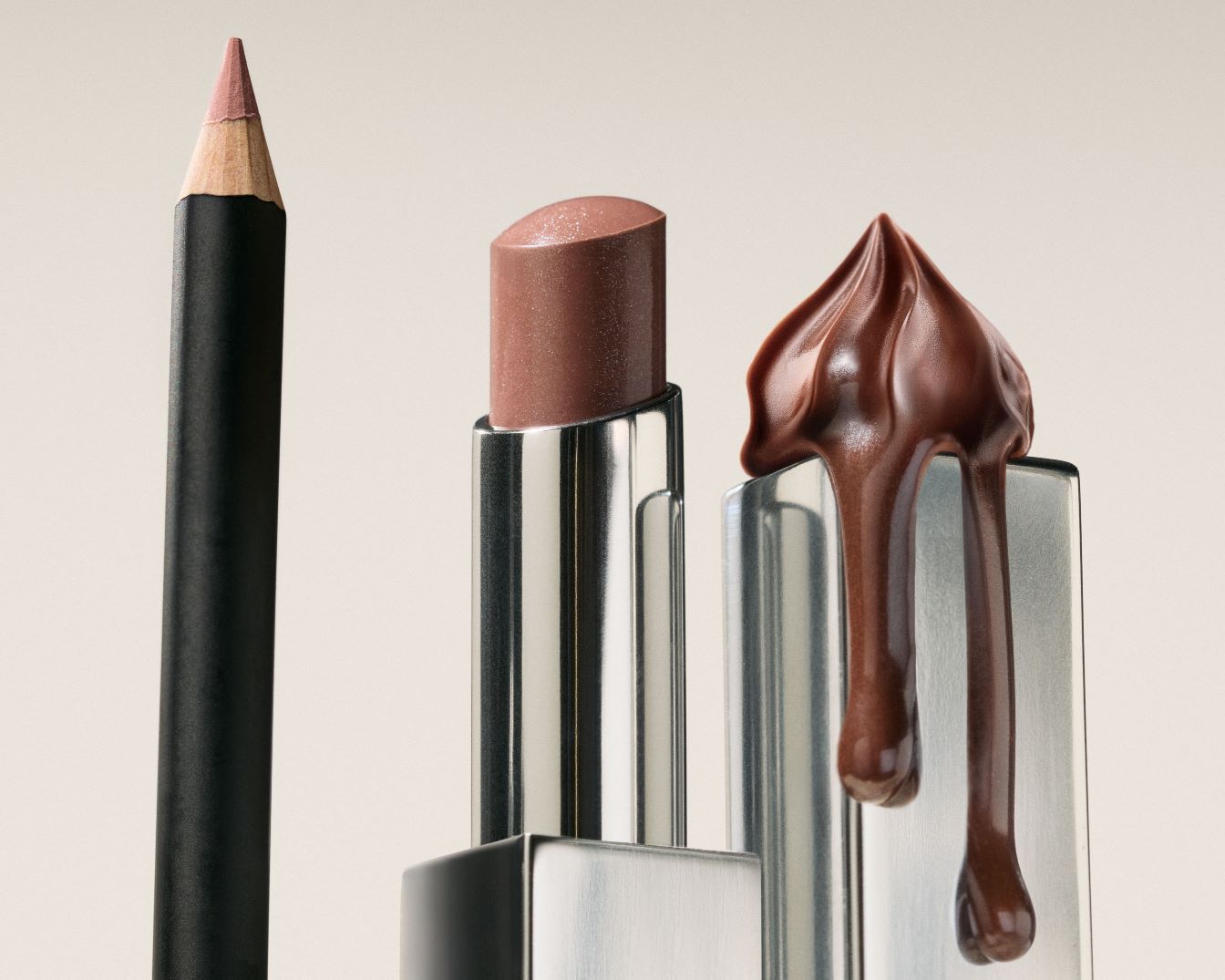 Nahaufnahme eines Lippenstifts in einem silbernen Gehäuse, eines schwarzen Lipliners und einer Schokoladencreme, die auf einem silbernen Behälter geschmolzen ist.