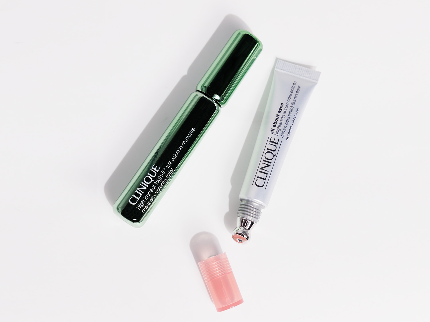 Ecco un mascara Clinique High Impact High-Fi™ Full Volume in una confezione verde lucida, accanto a un siero illuminante concentrato All About Eyes in un tubo bianco.