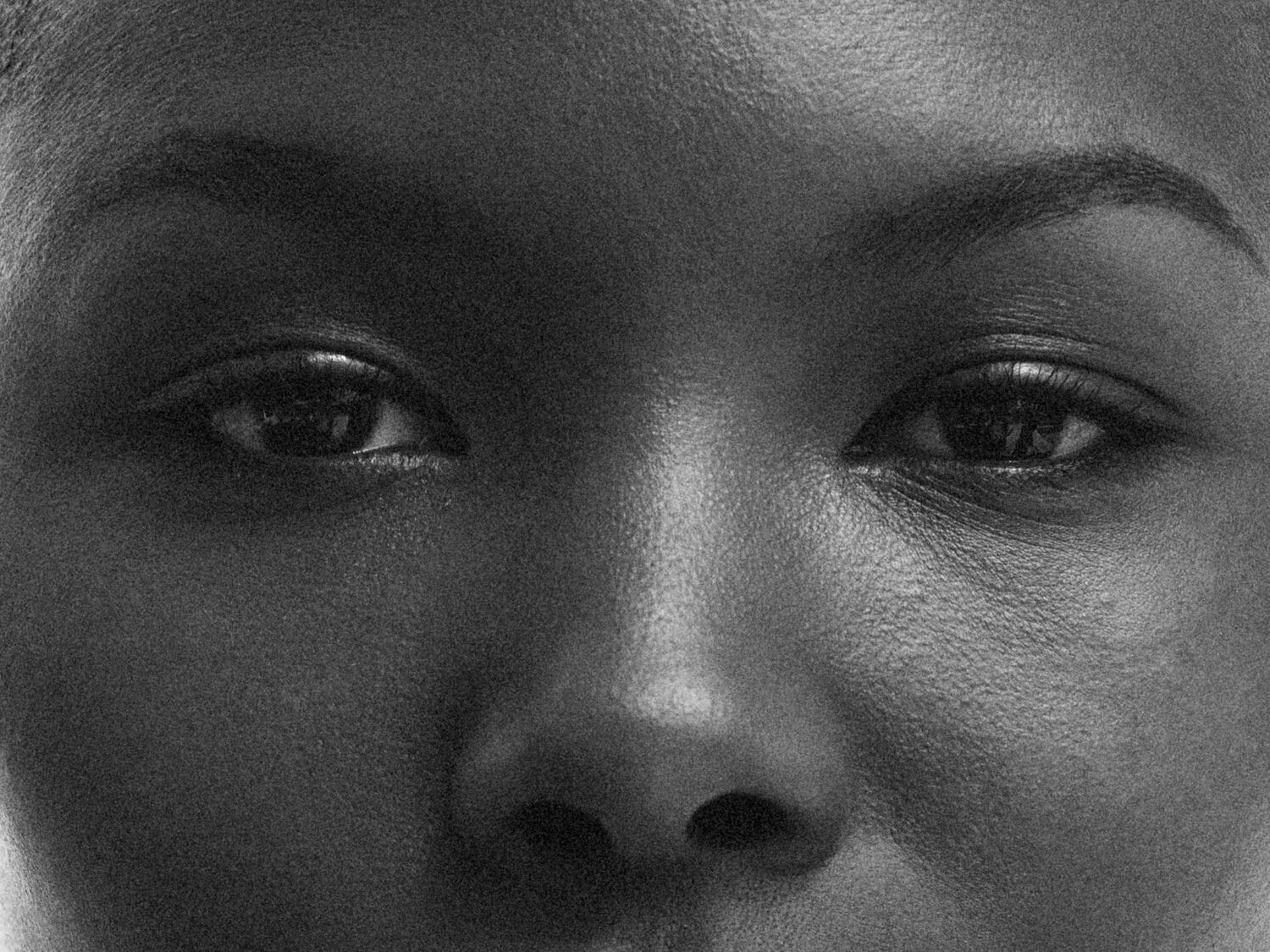 Nahaufnahme eines Frauengesichts mit Fokus auf Augen, Nase und Augenbrauen in Schwarzweiß.