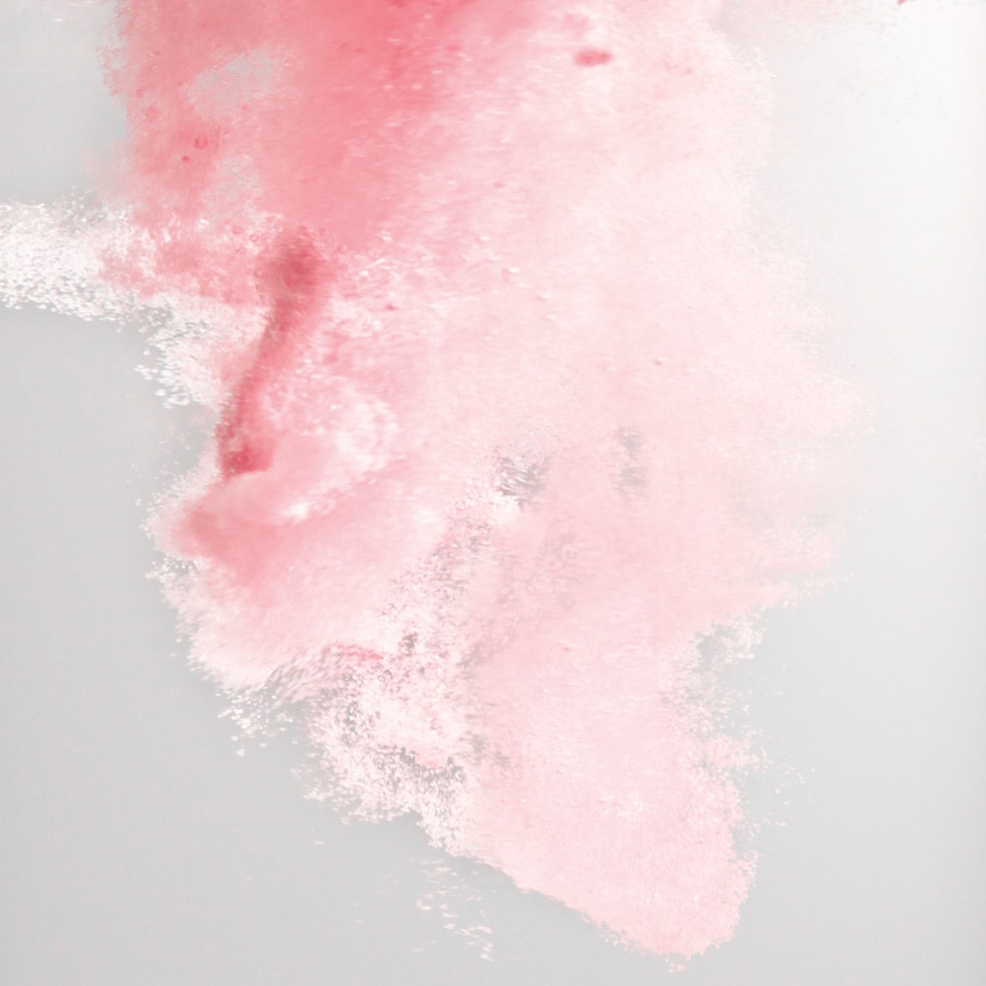 Zartrosa Farbwolke, die sich sanft in einem hellen Hintergrund ausbreitet und eine beruhigende und verträumte Atmosphäre schafft.