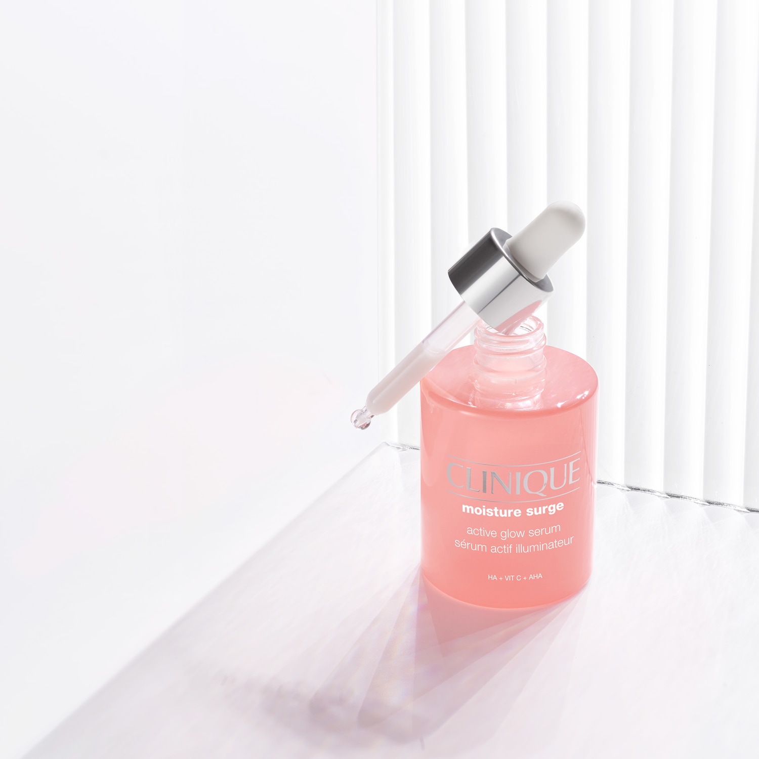 Das feuchtigkeitsspendende Serum von Clinique, Moisture Surge Active Glow, in einer durchsichtigen, hellrosa Flasche mit Pipette, verspricht einen strahlenden Teint dank Hyaluronsäure, Vitamin C und AHA.