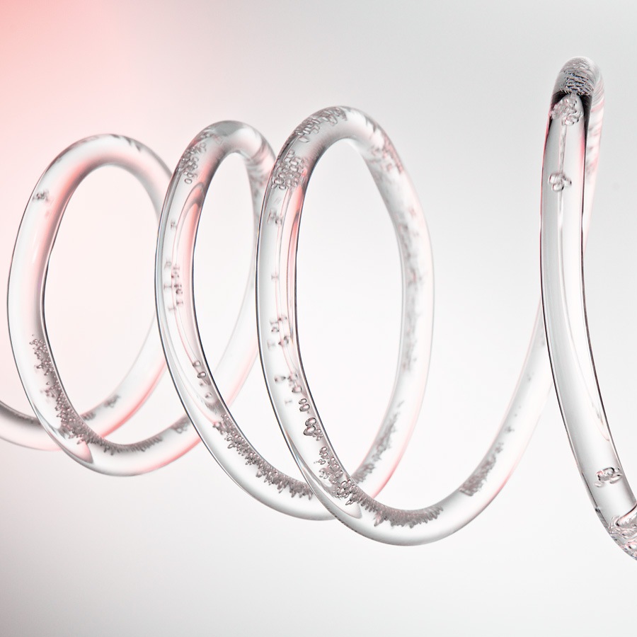 Nahaufnahme einer transparenten Spirale, die mit einer klaren Flüssigkeit gefüllt ist, in der sich kleine Bläschen bilden.
