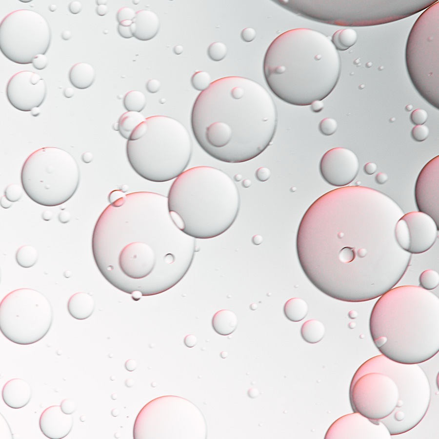 Nahaufnahme von transparenten Blasen unterschiedlicher Größe, die in einer klaren Flüssigkeit schweben und ein Gefühl von Reinheit und Feuchtigkeit vermitteln.