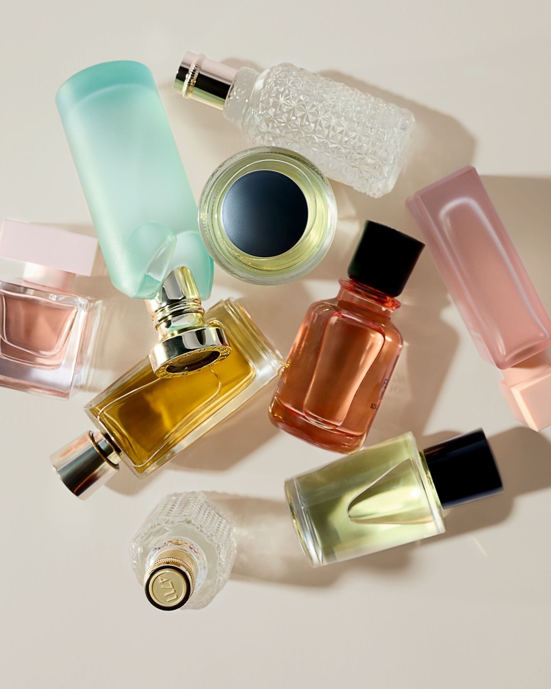 Įvairių formų ir spalvų kvepalų buteliukų kolekcija, įskaitant skaidrius, žalsvus, rausvus ir geltonus atspalvius.