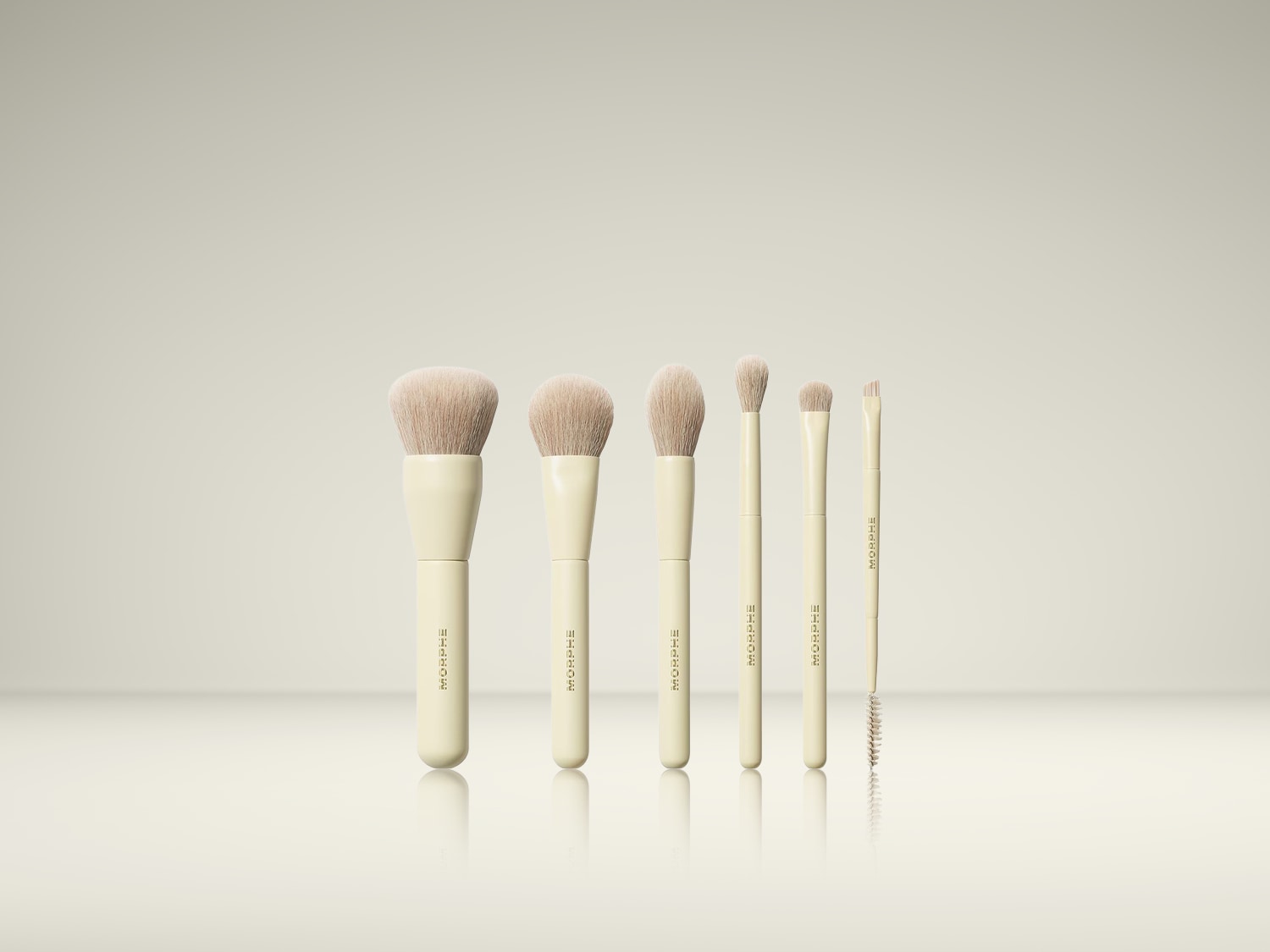 Een set van zes Morphe make-upborstels met crèmekleurige handvatten en zachte, lichtbruine haren, geschikt voor het aanbrengen van diverse make-upproducten.