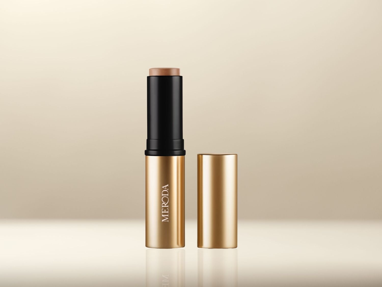 Gouden MERODA foundation stick met zwarte details en een losse dop, klaar om je teint te perfectioneren.