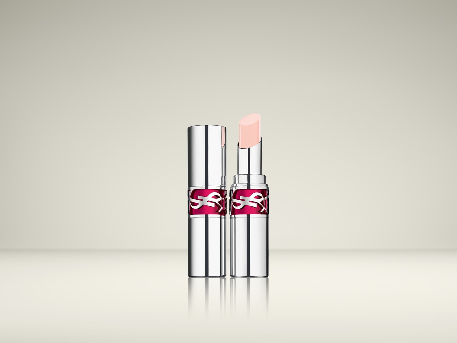 Twee YSL lippenbalsems in zilveren hulzen met het YSL-logo in het roze, waarvan één open is om de lichtroze balsem te laten zien.