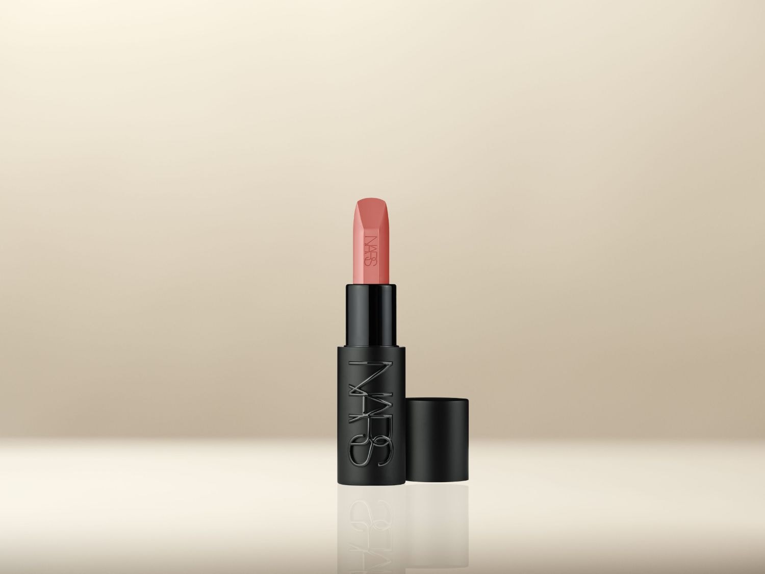 NARS lipstick in een zwarte huls met een perzikkleurige tint, klaar om je lippen te accentueren met een vleugje kleur.