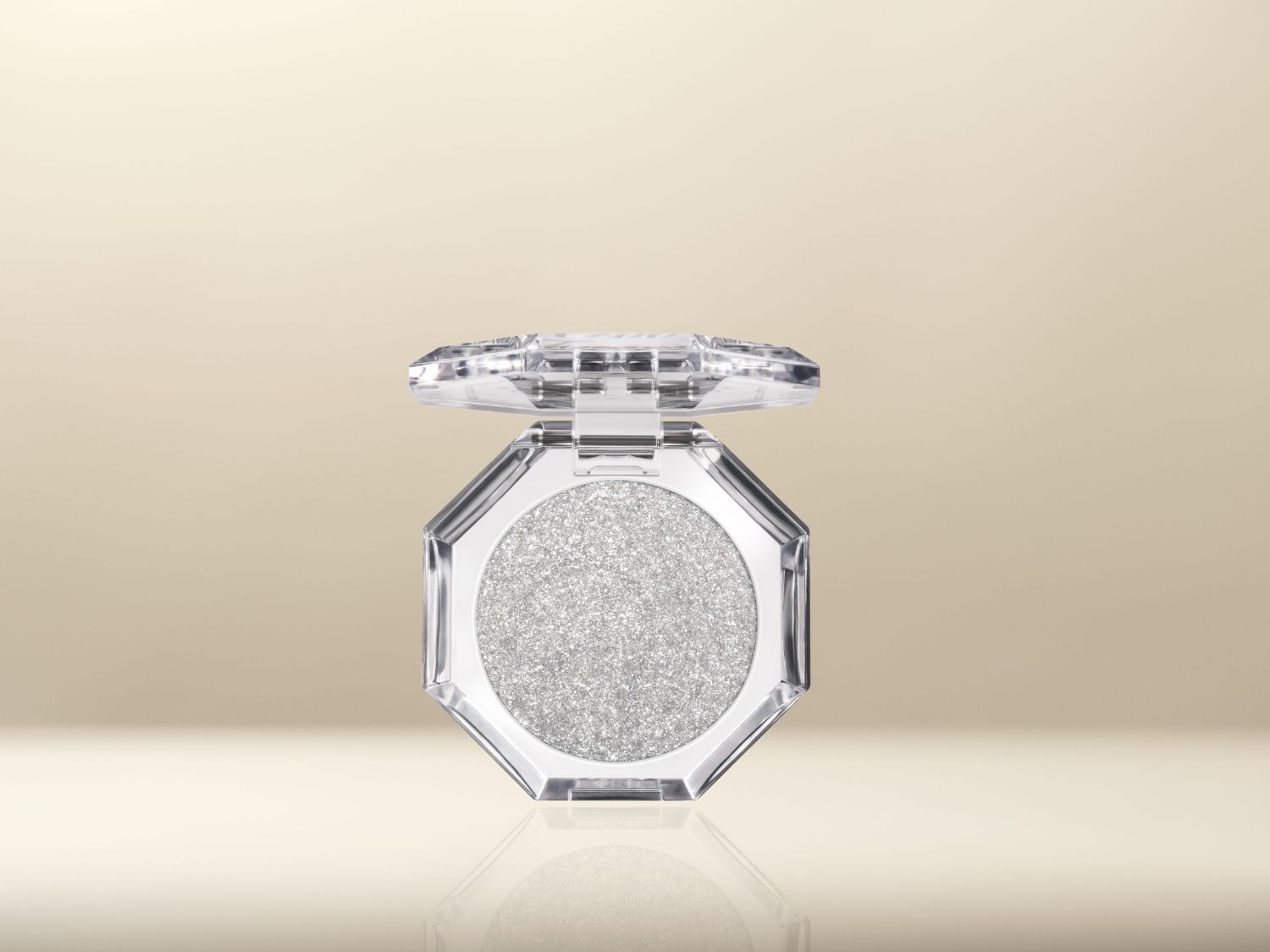 Een oogschaduw in een transparante, achthoekige verpakking met een zilveren glitterpoeder.