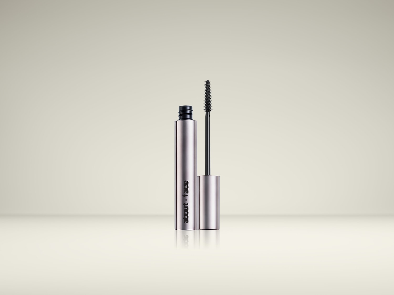 De About-Face mascara in een slanke, zilverkleurige tube met een zwarte applicatorborstel, perfect voor het creëren van gedefinieerde wimpers.