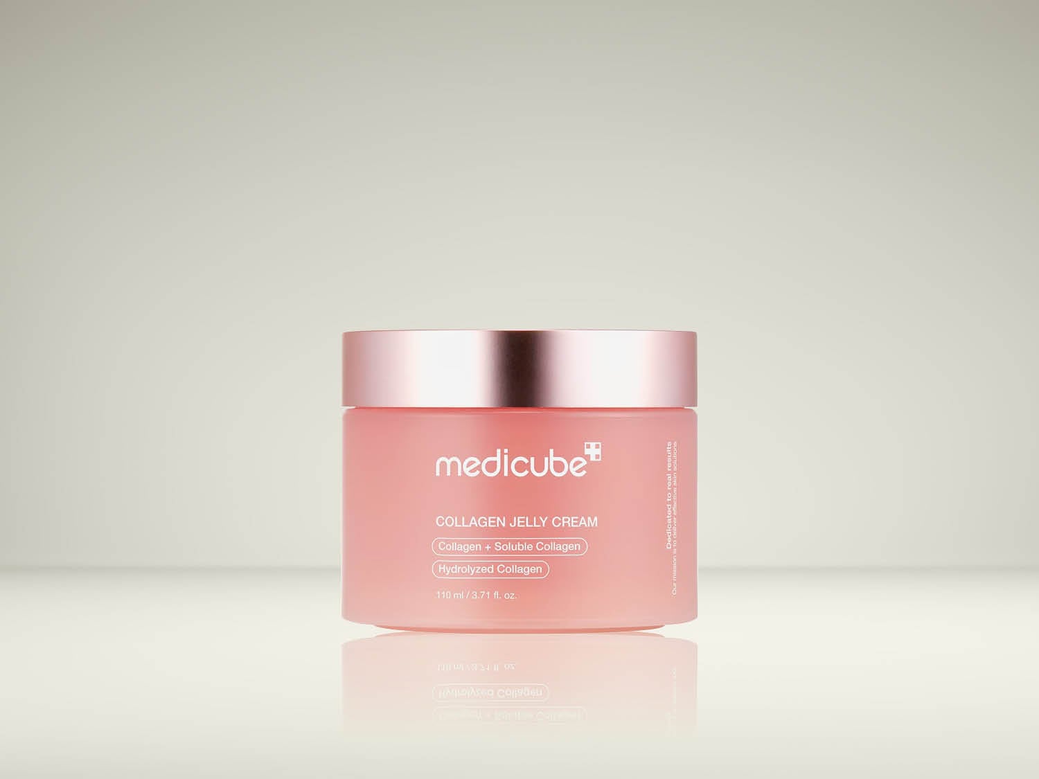 De Medicube Collagen Jelly Cream in een roze pot met een glanzende roségouden deksel, met de tekst "Dedicated to real results" aan de zijkant, bevat 110 ml/3,71 fl. oz. van een formule met collageen, oplosbaar collageen en gehydrolyseerd collageen.