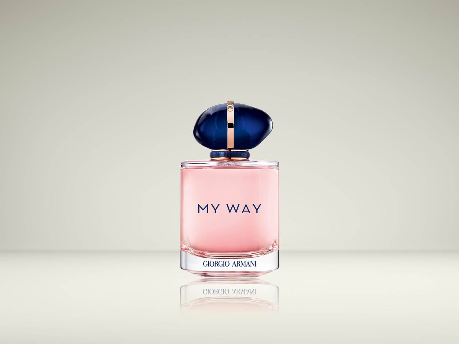 De Giorgio Armani My Way Eau de Parfum is een roze vloeistof in een transparante fles met een donkerblauwe, onregelmatig gevormde dop en een gouden ring, staand op een reflecterend oppervlak.