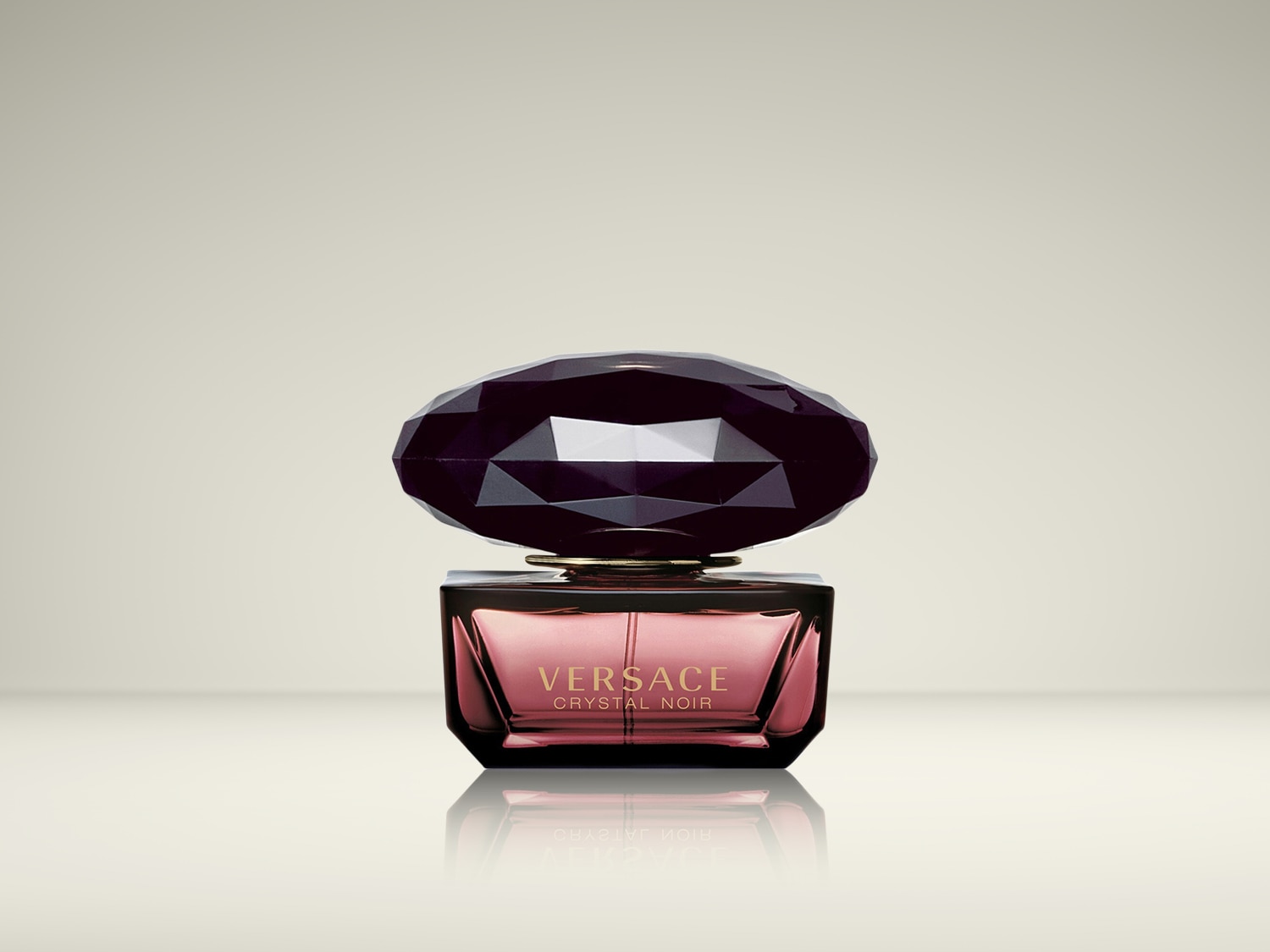 Versace Crystal Noir Eau de Parfum presenteert zich in een elegante, donkerroze flacon met een grote, donkere kristallen dop.