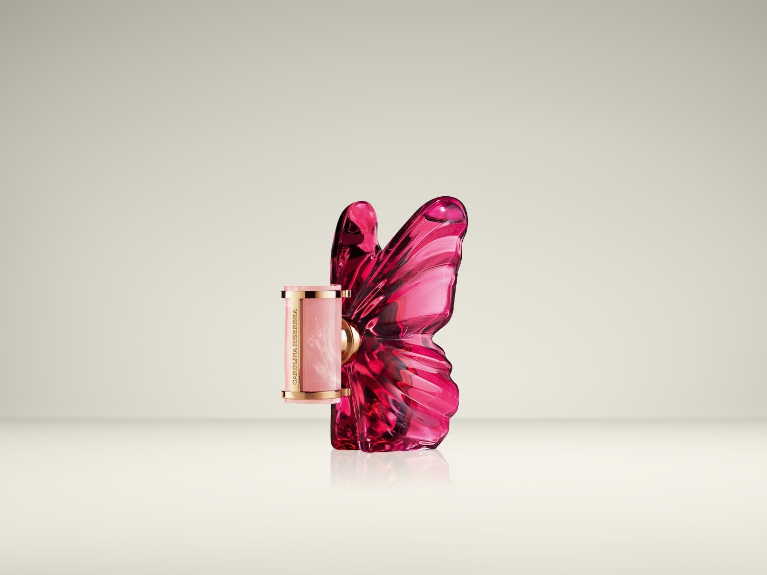 Een roze lippenstift met de merknaam "CAROLINA HERRERA" in goudkleurige letters, staat naast een felroze vlindervormige parfumfles.