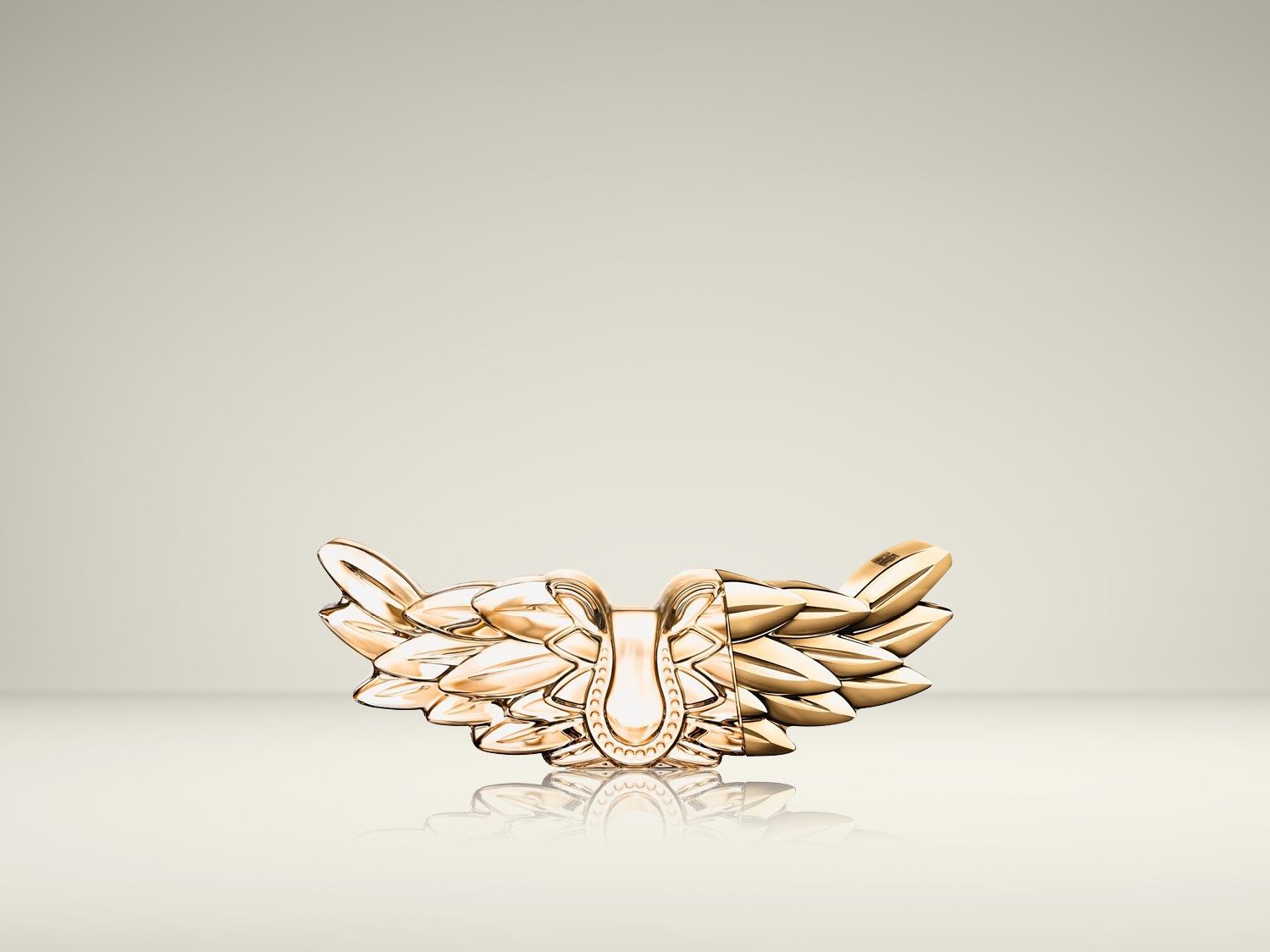 Un ornement doré complexe, évoquant des ailes stylisées ou des feuilles disposées symétriquement, repose sur une surface réfléchissante.