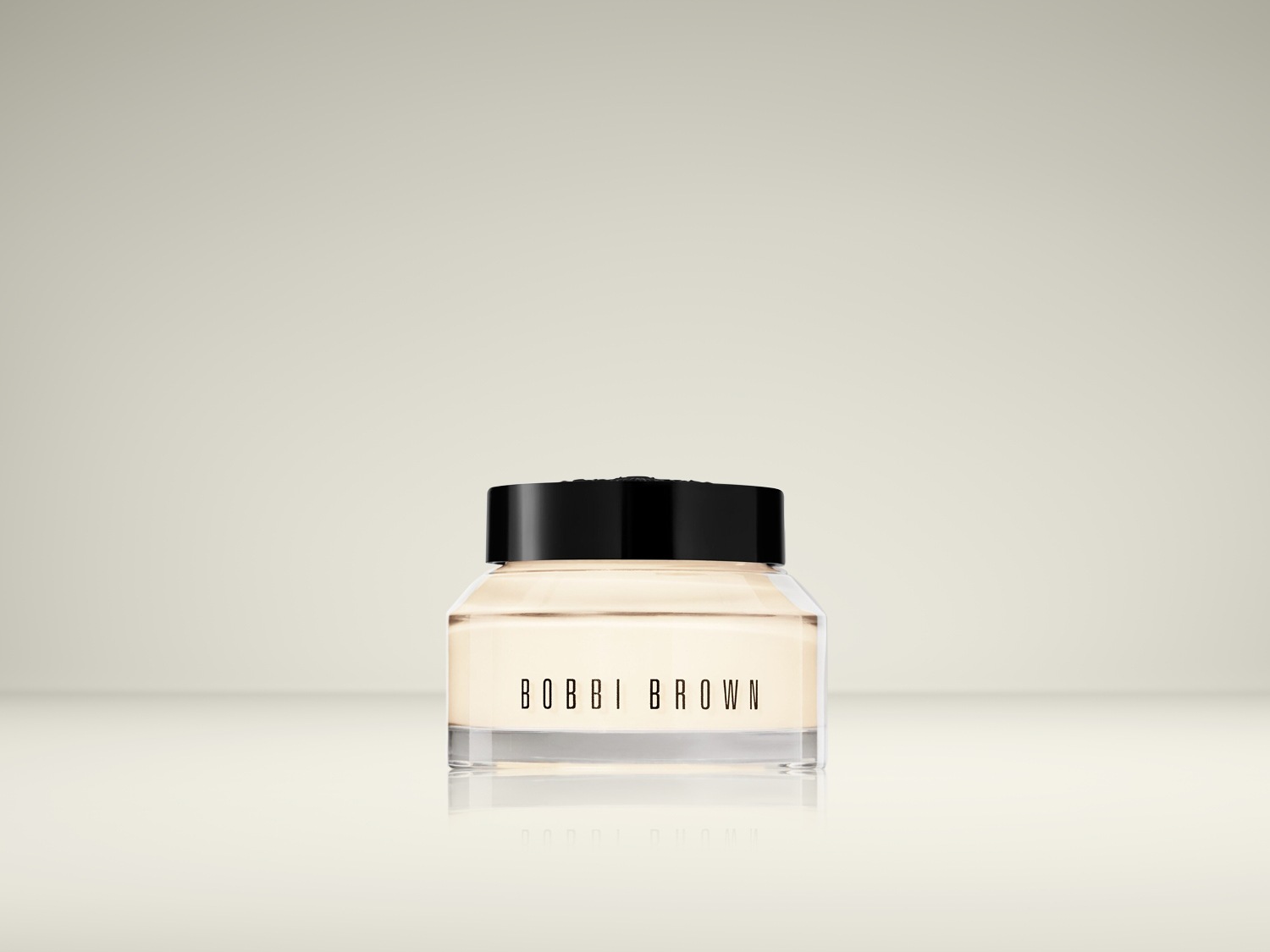 Voici un pot transparent de crème Bobbi Brown avec un couvercle noir, parfait pour hydrater et préparer votre peau.
