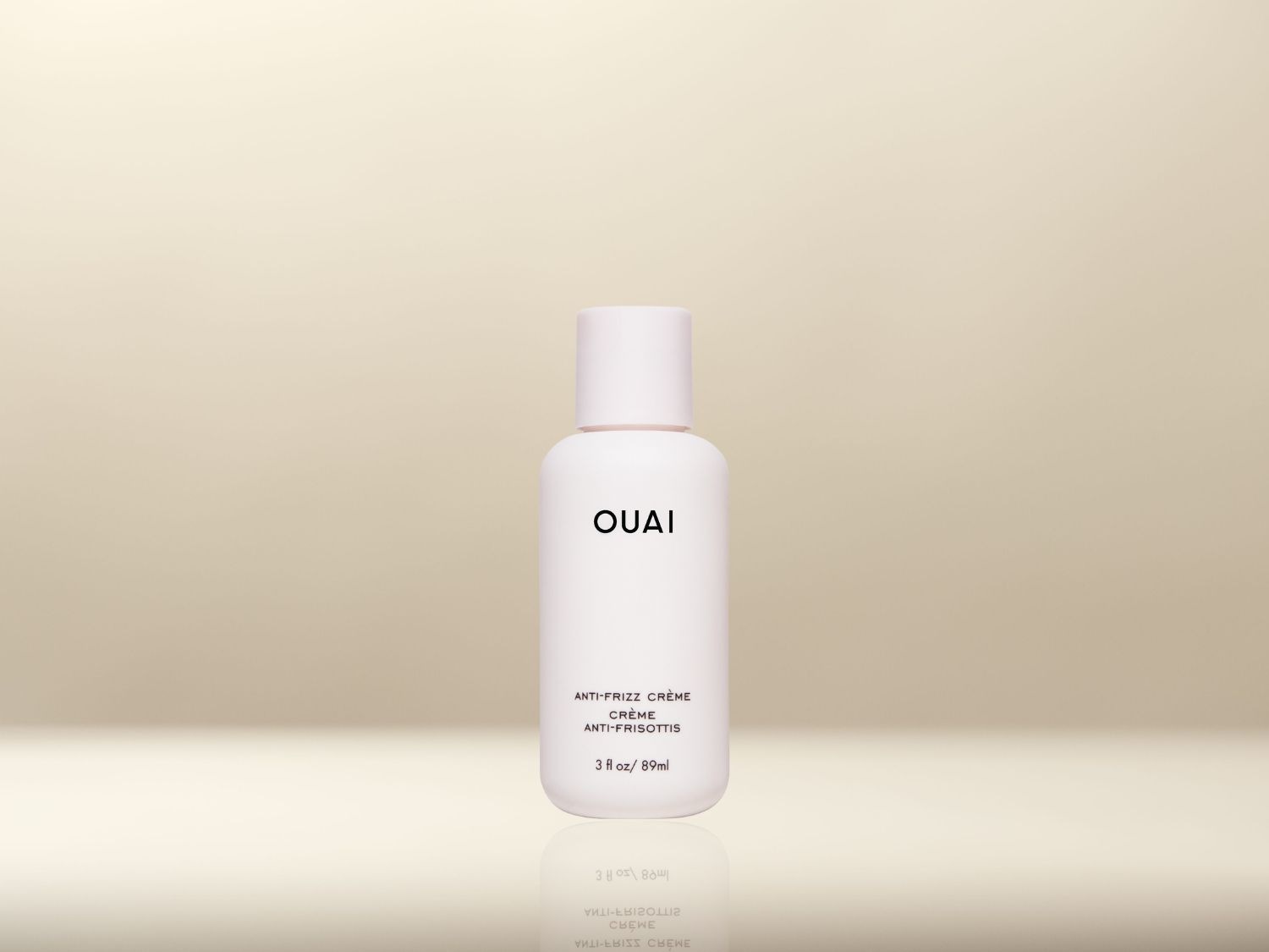 Voici un flacon blanc de 89 ml de crème anti-frizz OUAI, conçu pour lisser les cheveux et éliminer les frisottis.