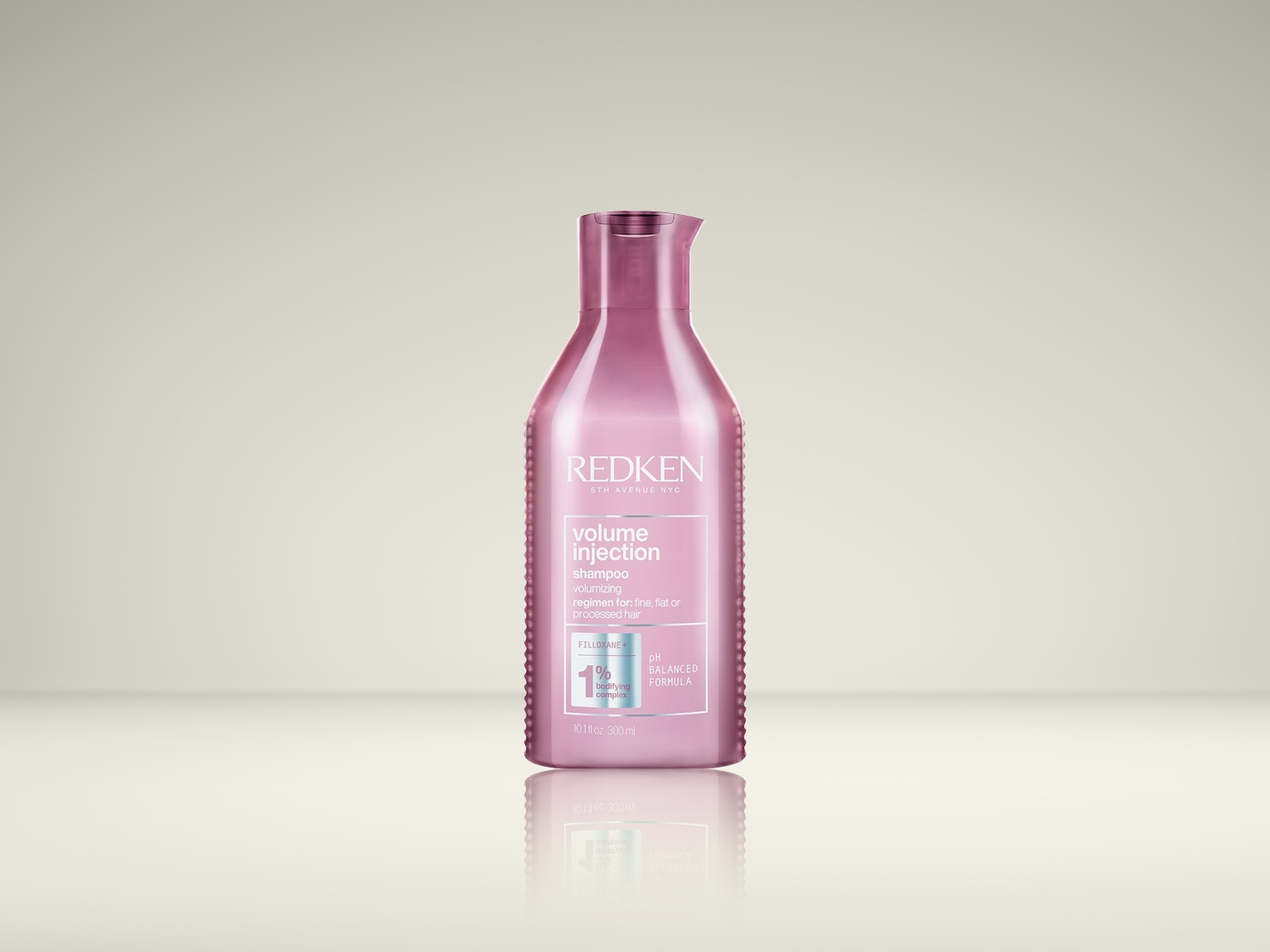 Voici un flacon rose de shampooing Redken Volume Injection, conçu pour donner du volume aux cheveux fins, plats ou traités, avec une formule équilibrée au pH et un complexe fortifiant à 1 %.