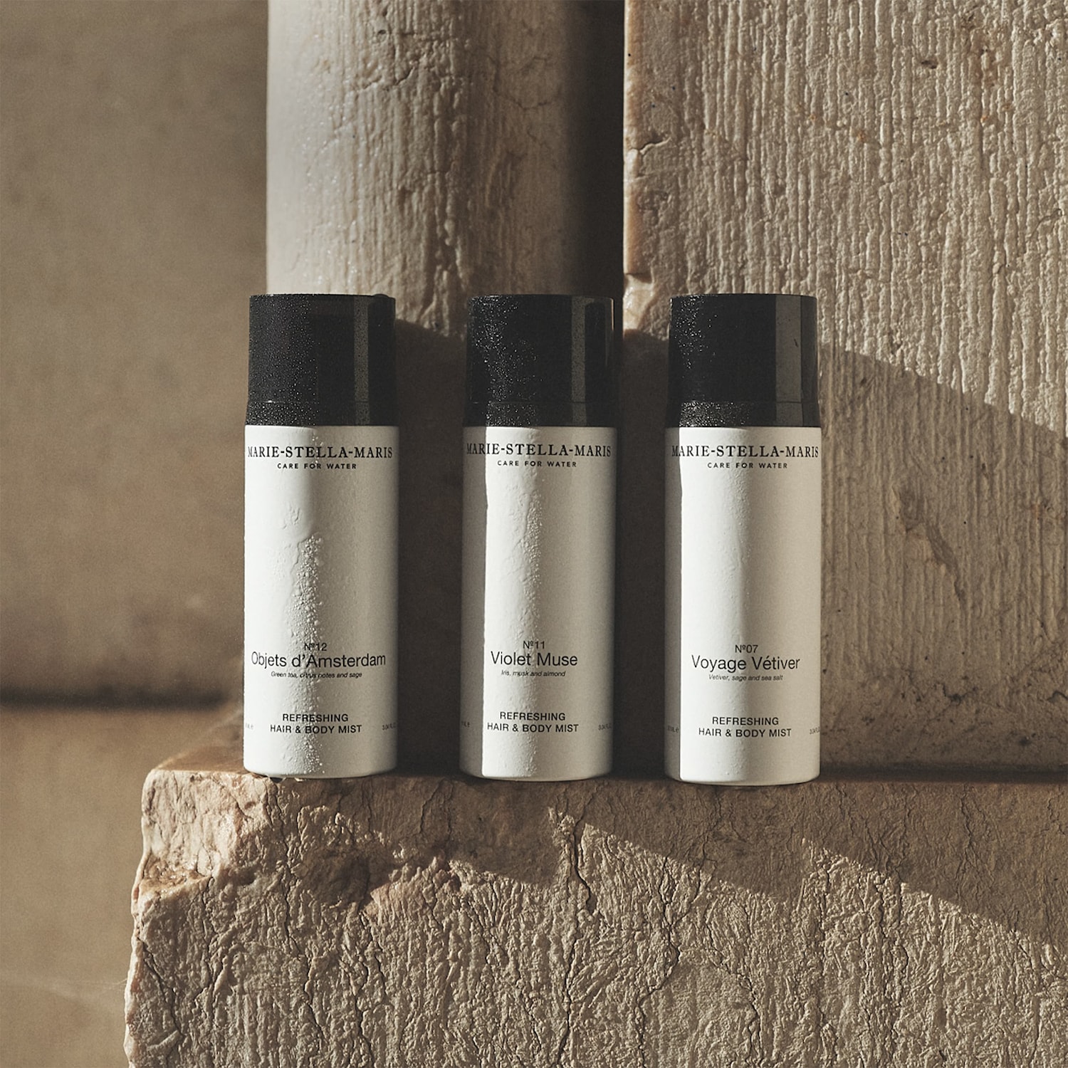 Drie witte Marie-Stella-Maris haar- en bodymists met zwarte doppen, elk met een unieke geur: Objets d'Amsterdam, Violet Muse en Voyage Vétiver.