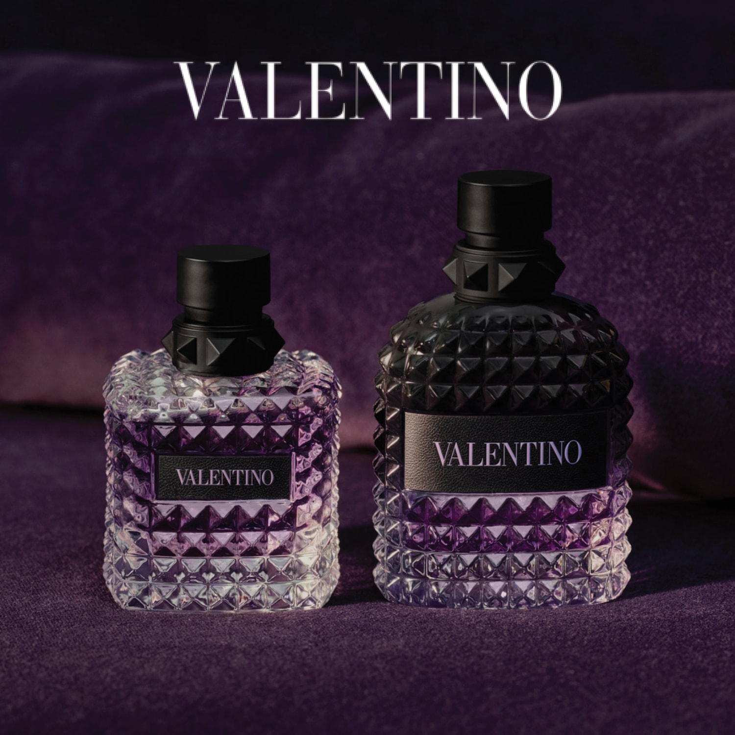 Twee Valentino-parfums staan op een paarse achtergrond, de flessen hebben een noppenpatroon en een zwarte dop.