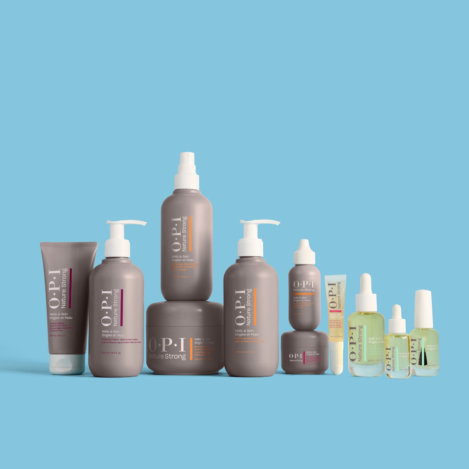 Een collectie OPI Nature Strong nagel- en huidverzorgingsproducten in grijze en transparante flessen met witte doppen, variërend van crèmes tot oliën, staat op een lichtblauwe achtergrond.