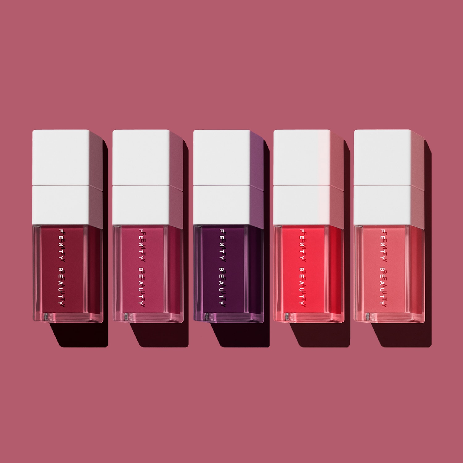 Découvrez la collection Fenty Beauty, présentant cinq teintes vibrantes de rouges à lèvres liquides dans des emballages carrés élégants avec des bouchons blancs.