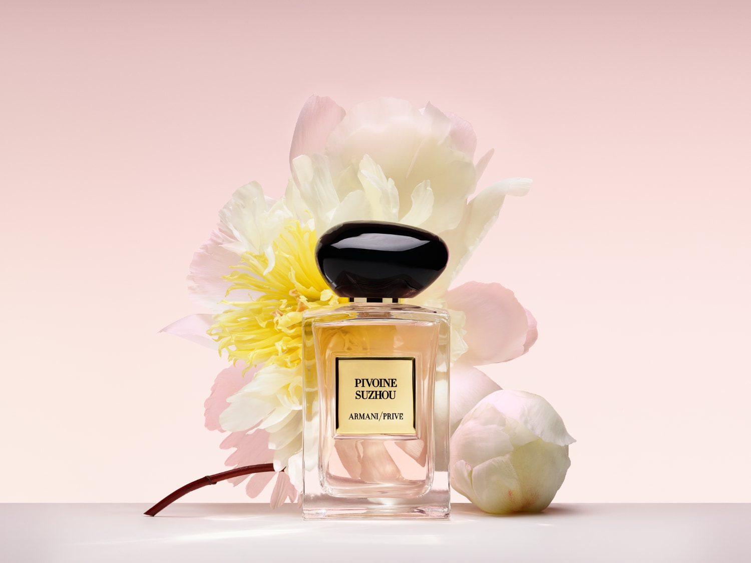 Az Armani/Privé Pivoine Suzhou parfüm üvegben, fekete kupakkal, virágos háttérrel elegáns és kifinomult illatot sugall.
