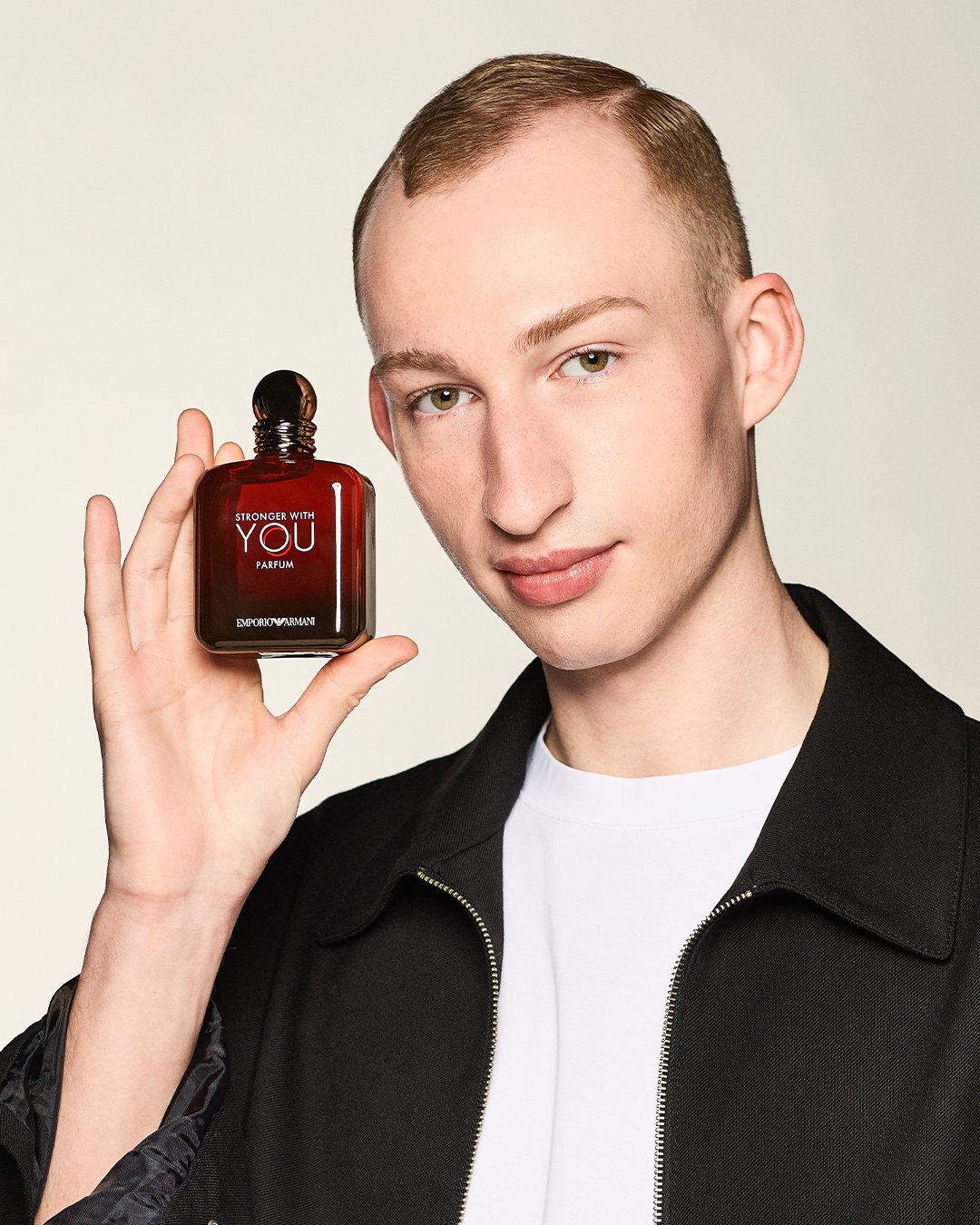 Eine strahlende Frau hält einen rosa Gucci-Duft mit Blumenmuster in der Hand und lächelt, während sie die Augen geschlossen hat.