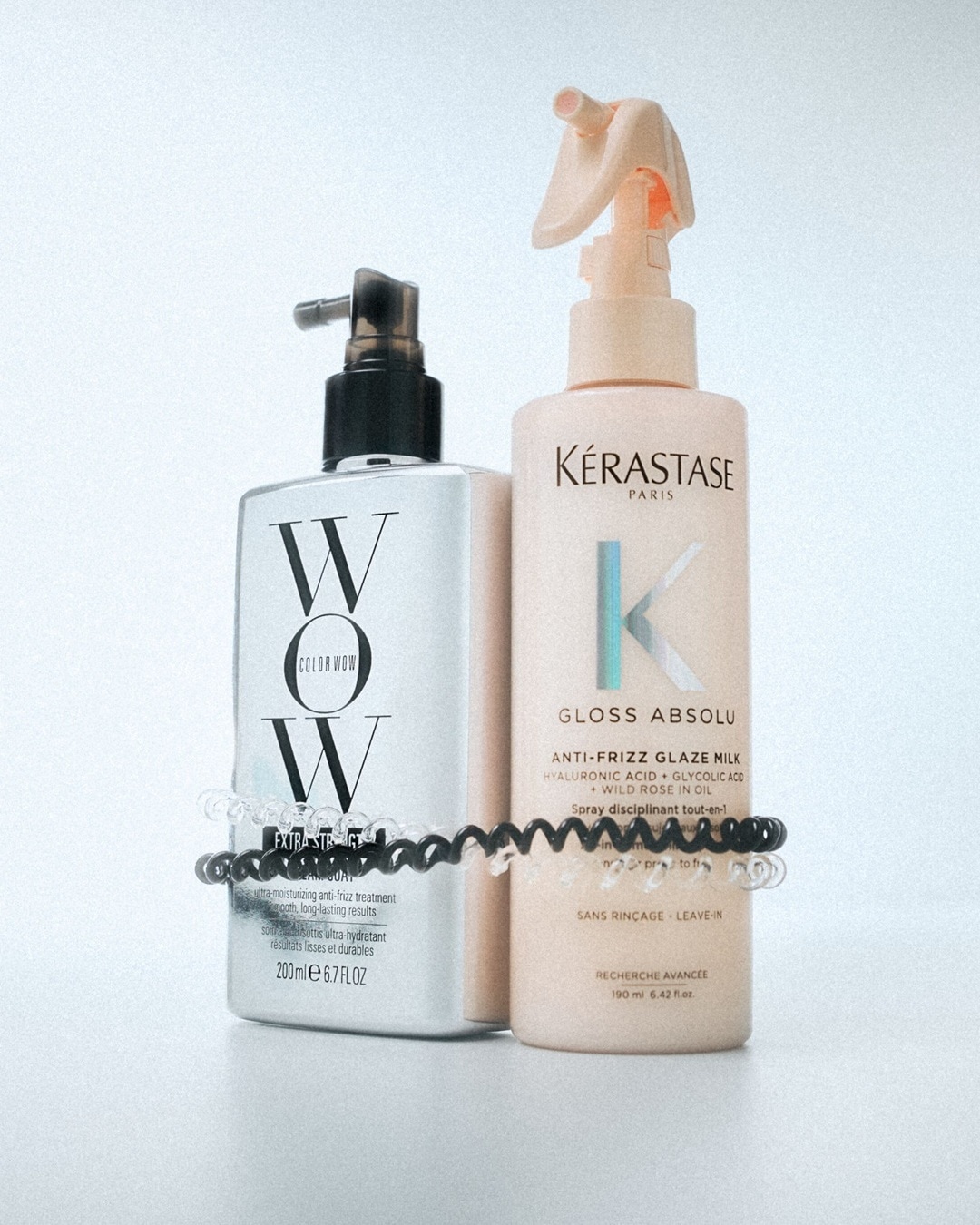 Zwei Anti-Frizz-Haarprodukte: Color Wow Extra Strict und Kérastase Paris Gloss Absolu Glaze Milk, beide mit feuchtigkeitsspendenden und glättenden Eigenschaften.