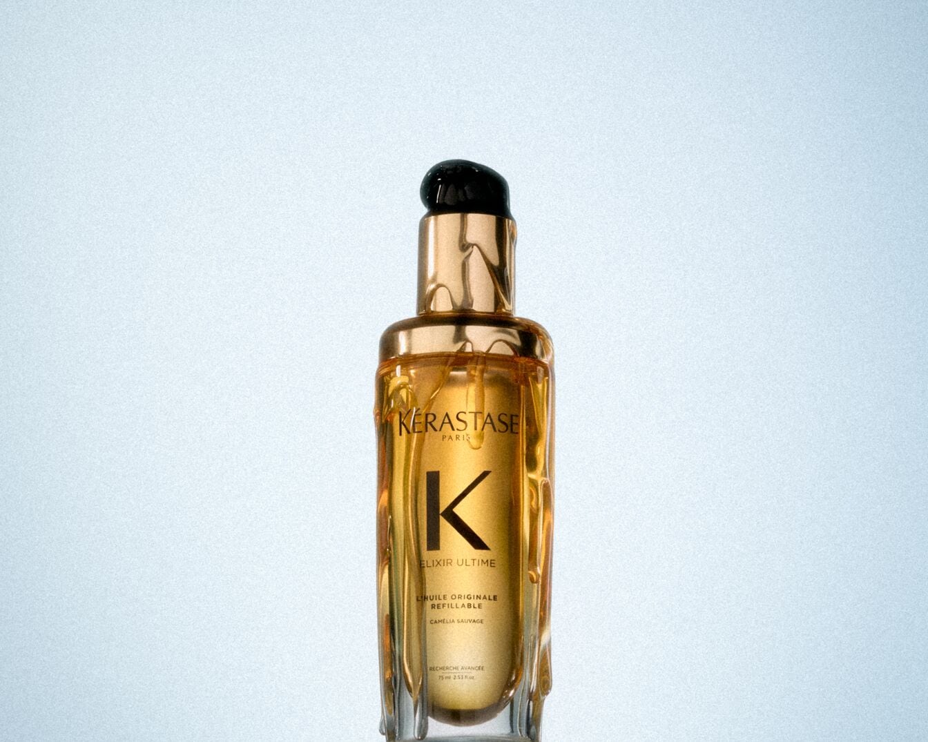 Nahaufnahme einer goldenen Flasche Kérastase Elixir Ultime L'Huile Originale mit einem schwarzen Verschluss.